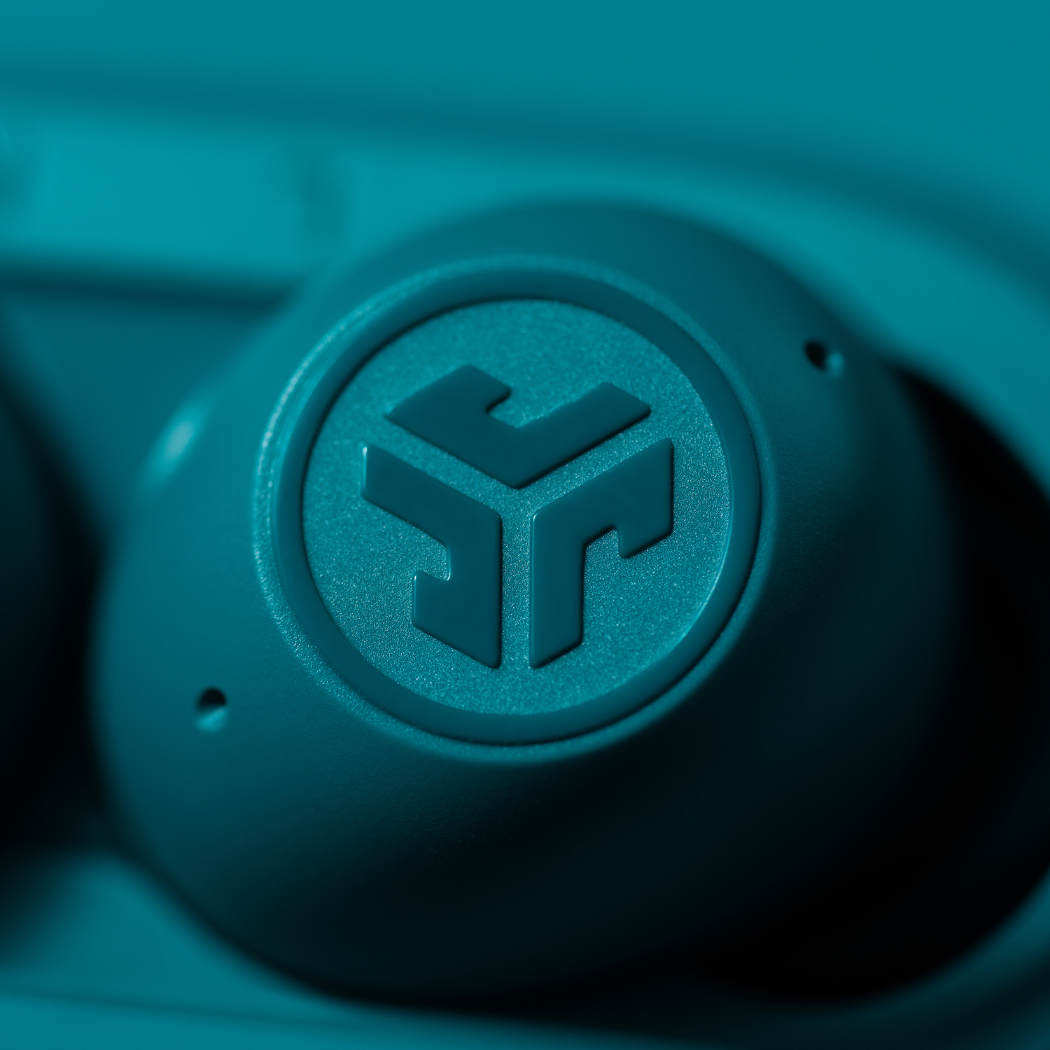 Close-up van teal oortelefoon met JLab-logo.