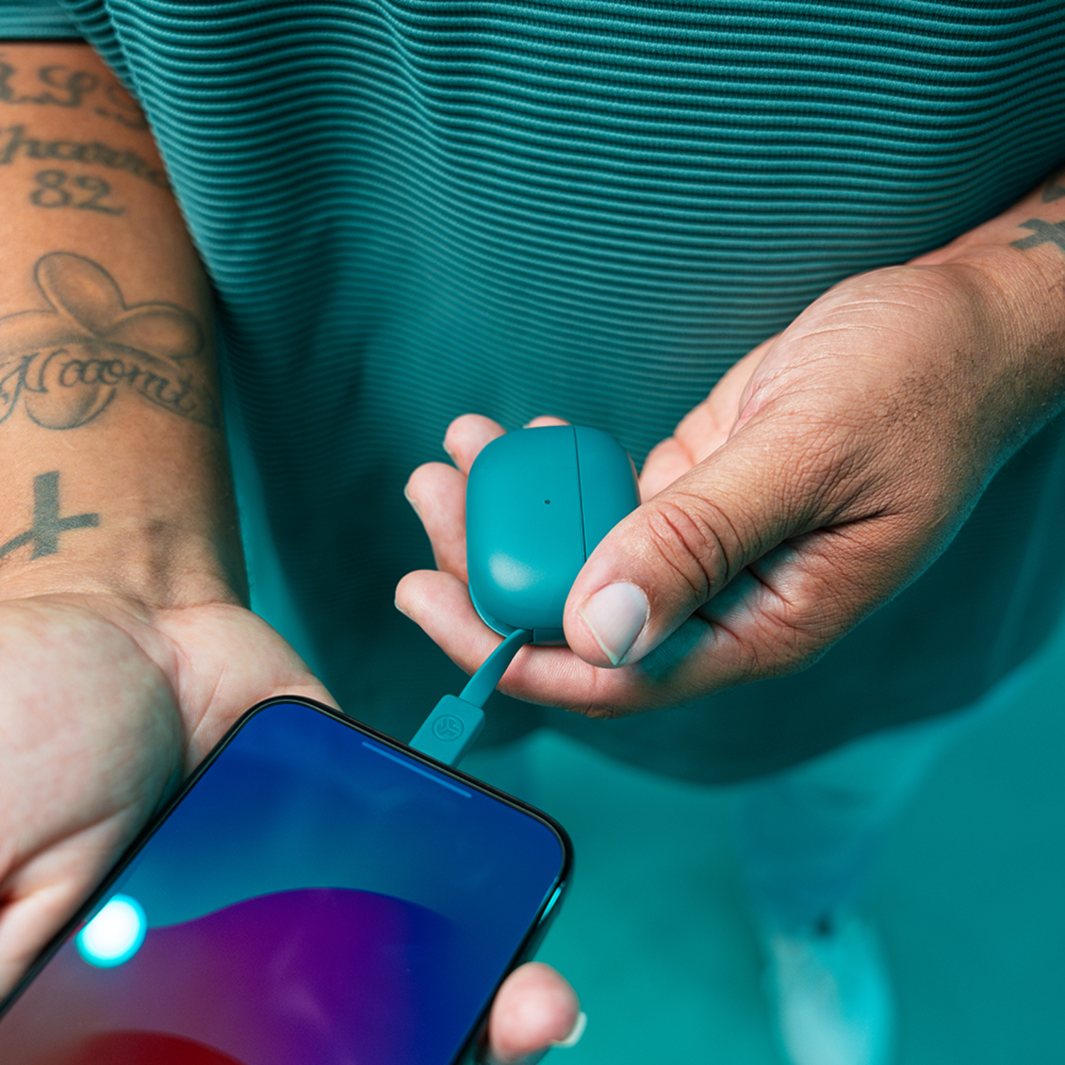 Een hand houdt een teal oplaadcase vast die is aangesloten op een telefoon.