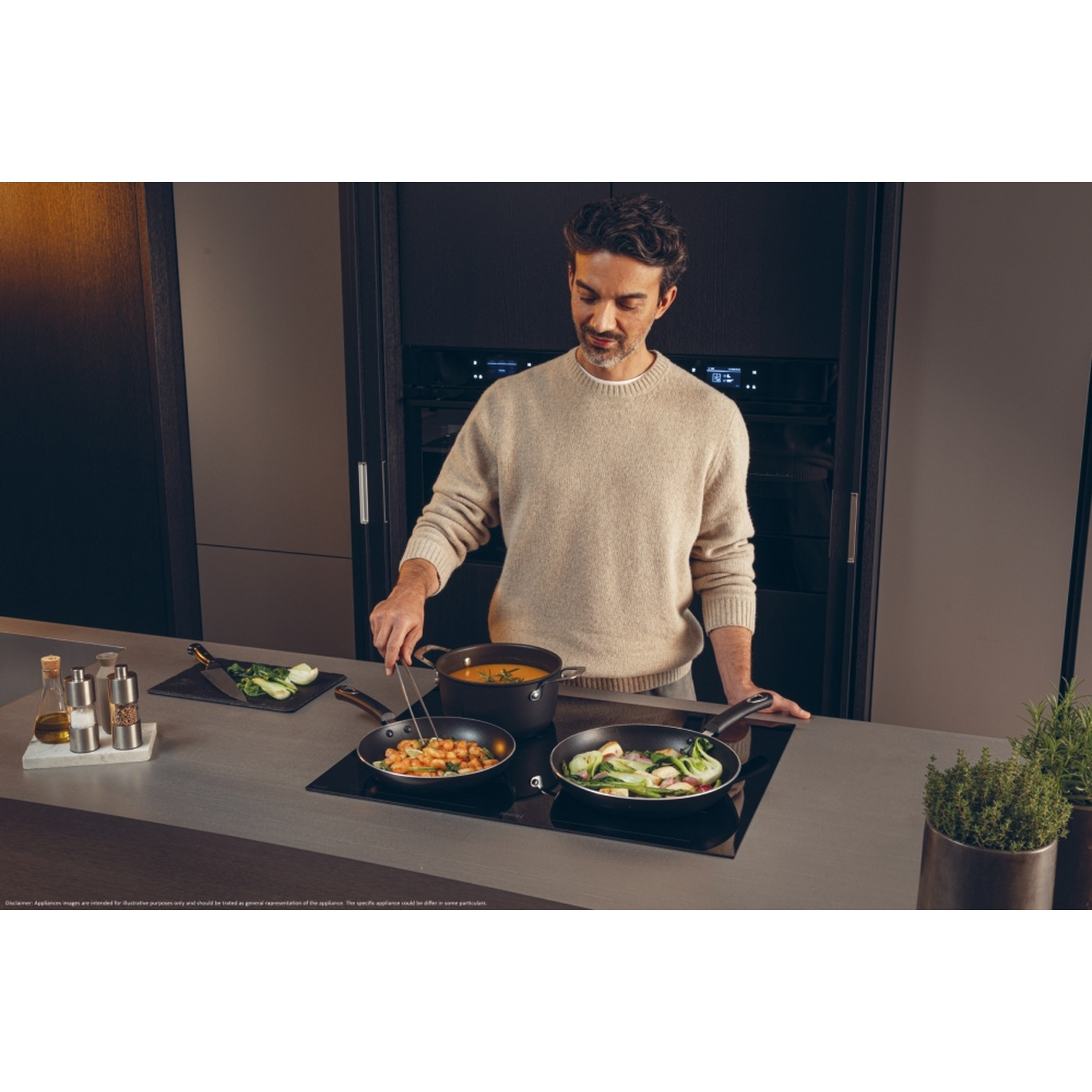 Uomo che cucina su un piano cottura Haier con padelle, pinze e verdure. Ambientazione cucina.