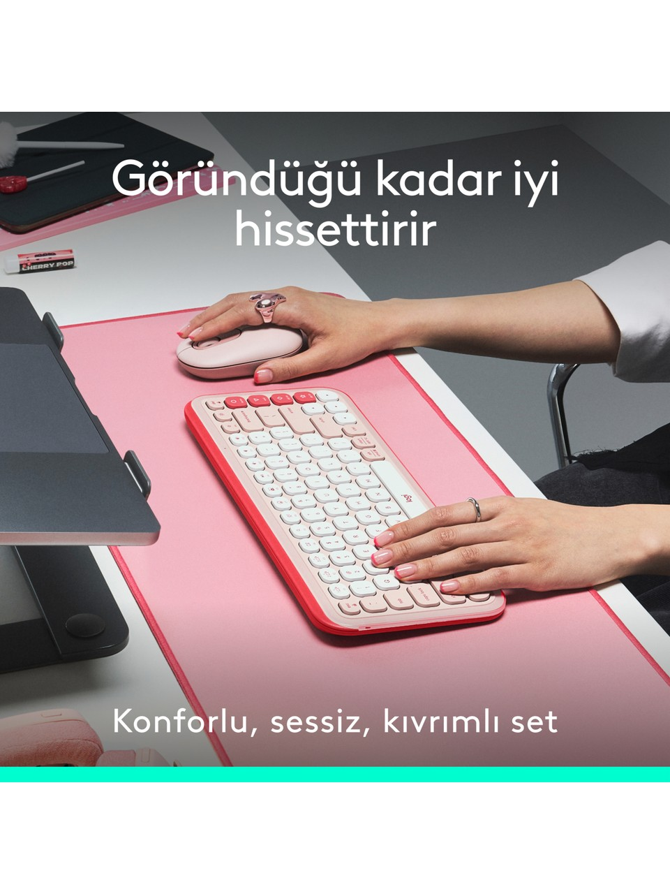 Beyaz bir masada pembe bir klavye ve fare kullanan bir kişi. Türkçe metin.