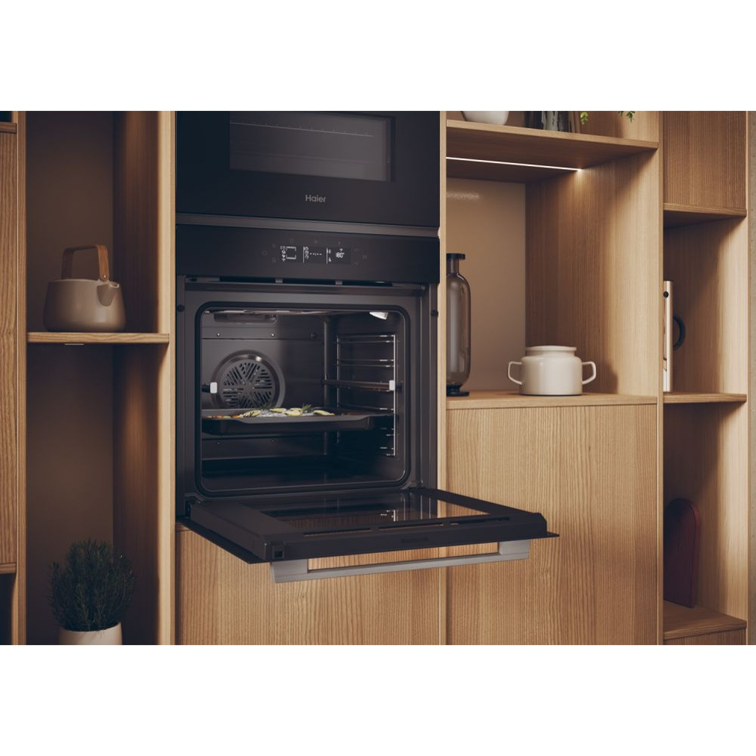 Un forno aperto è incassato in un mobile di legno, con oggetti e una pianta.