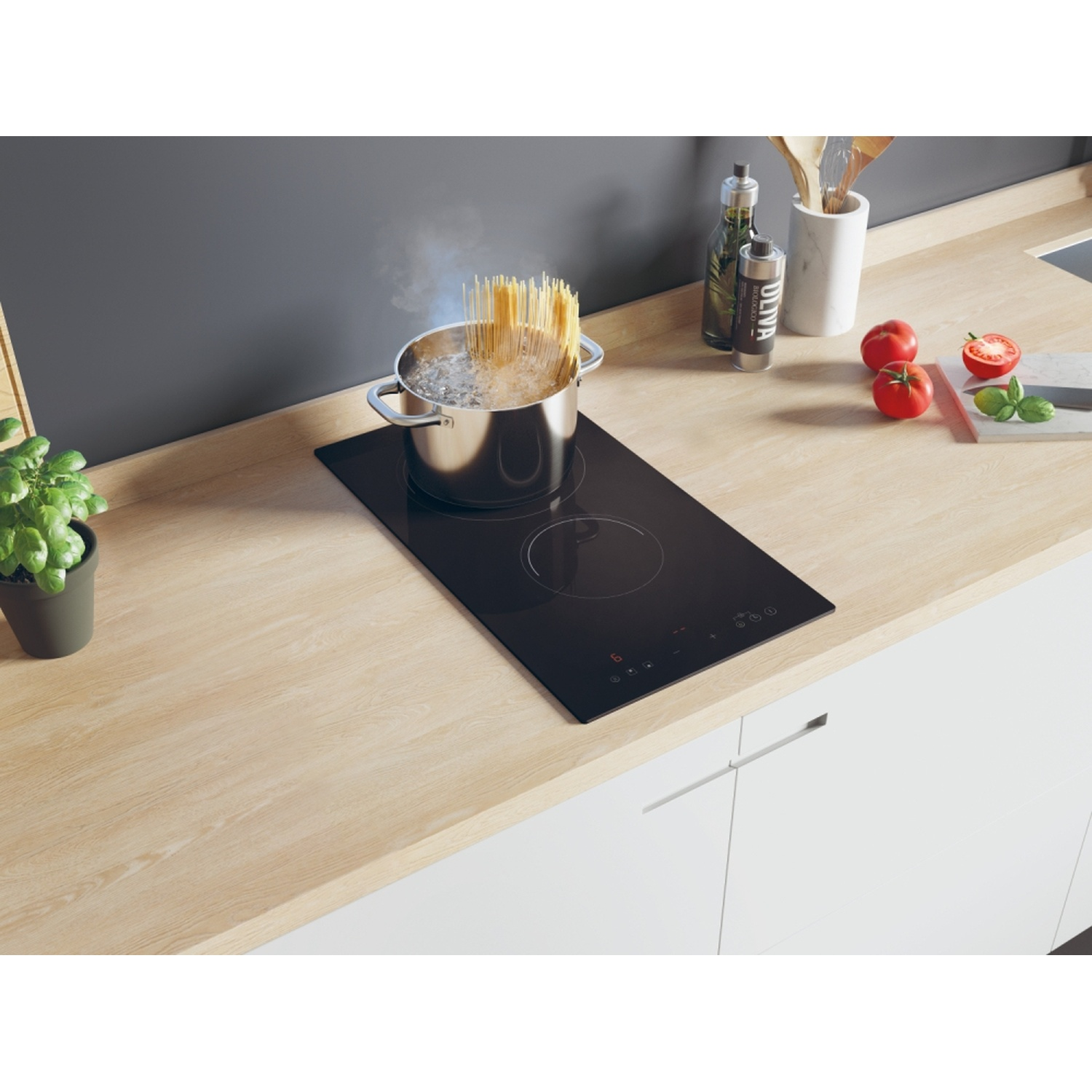 Un piano cottura a induzione Candy nero con pasta che bolle in una pentola. Scena di cucina con pomodori e olio.
