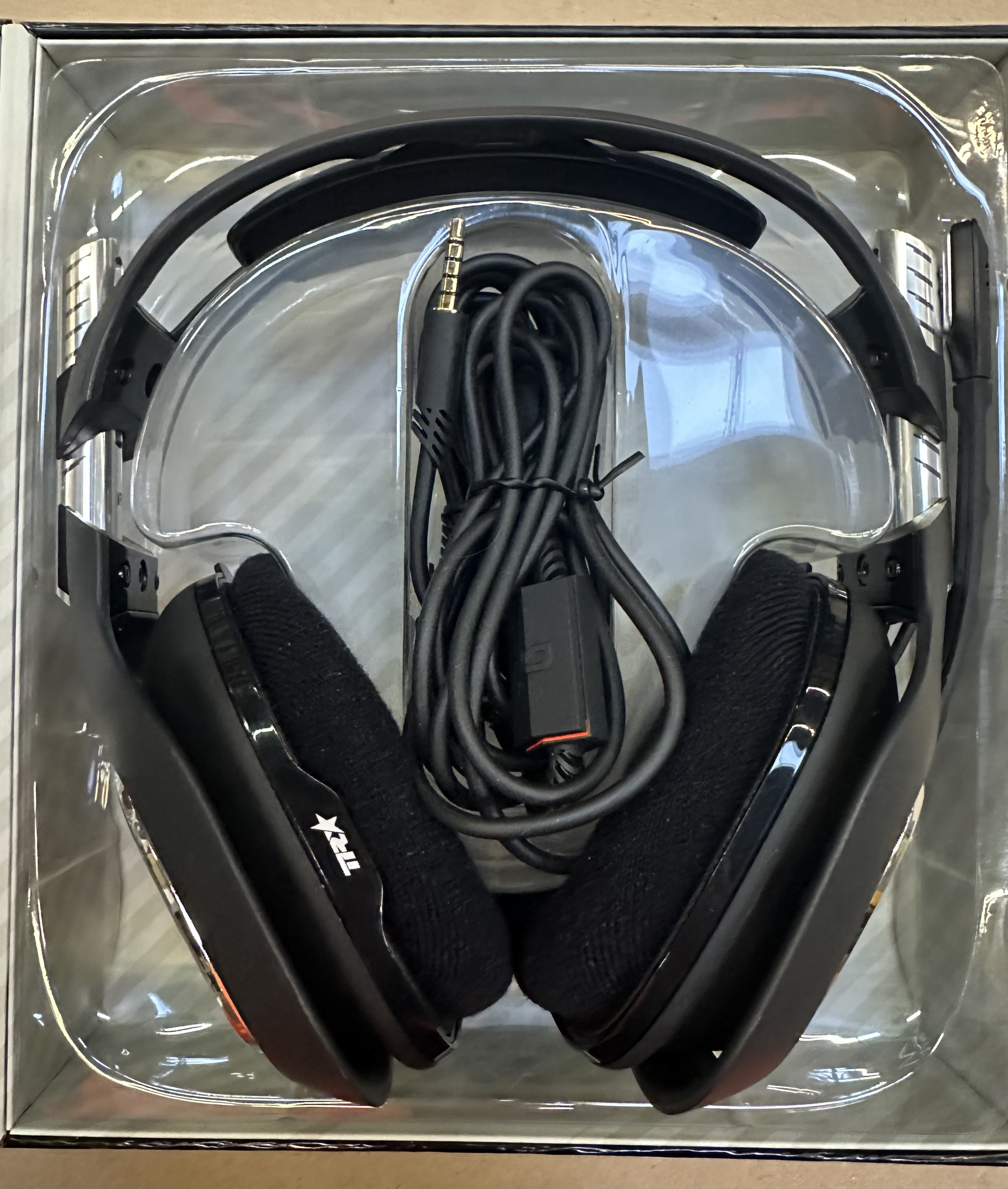 Czarne słuchawki dla graczy w przezroczystym plastikowym etui. Słuchawki mają mikrofon.