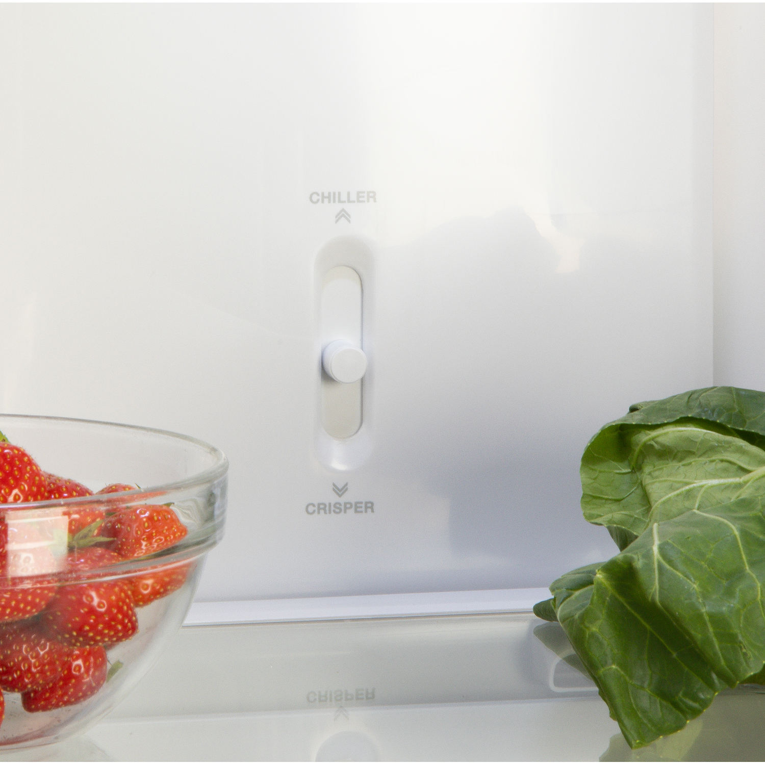 Close-up of refrigerator features: chiller and crisper controls, and strawberries.