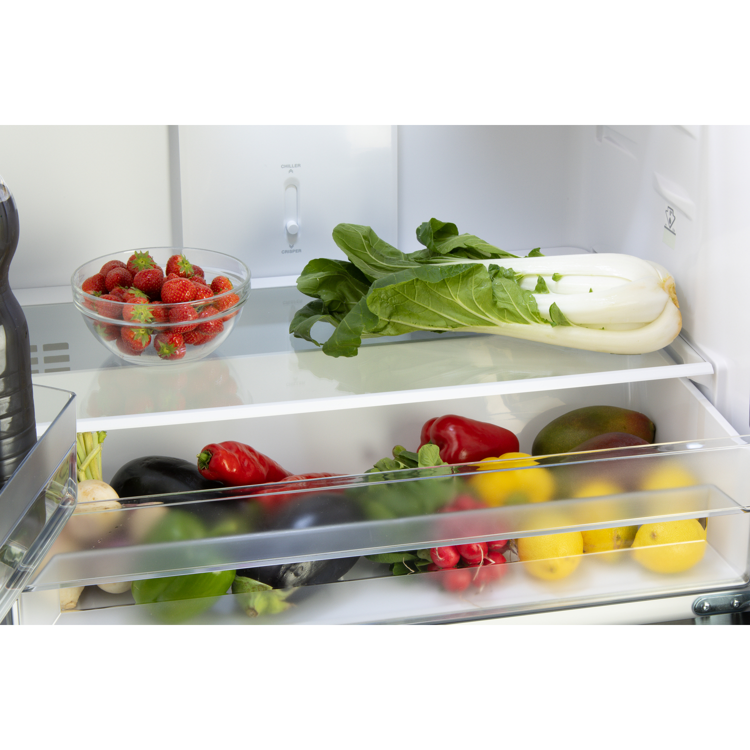 A fridge interior with fruits and vegetables in drawers and on shelves.