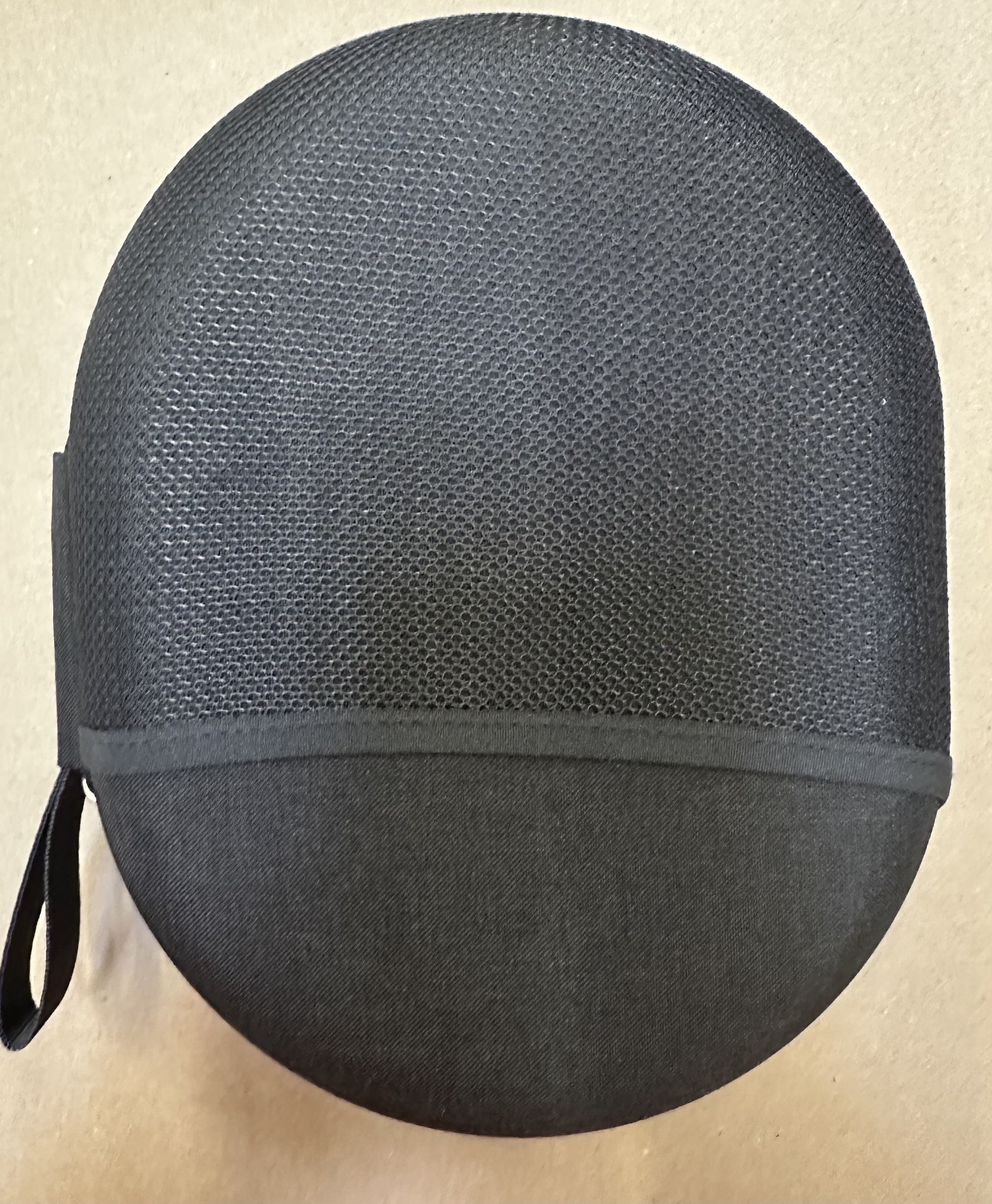 Czarny owalny futerał z siatkowym wierzchem. Czarny uchwyt jest z boku.