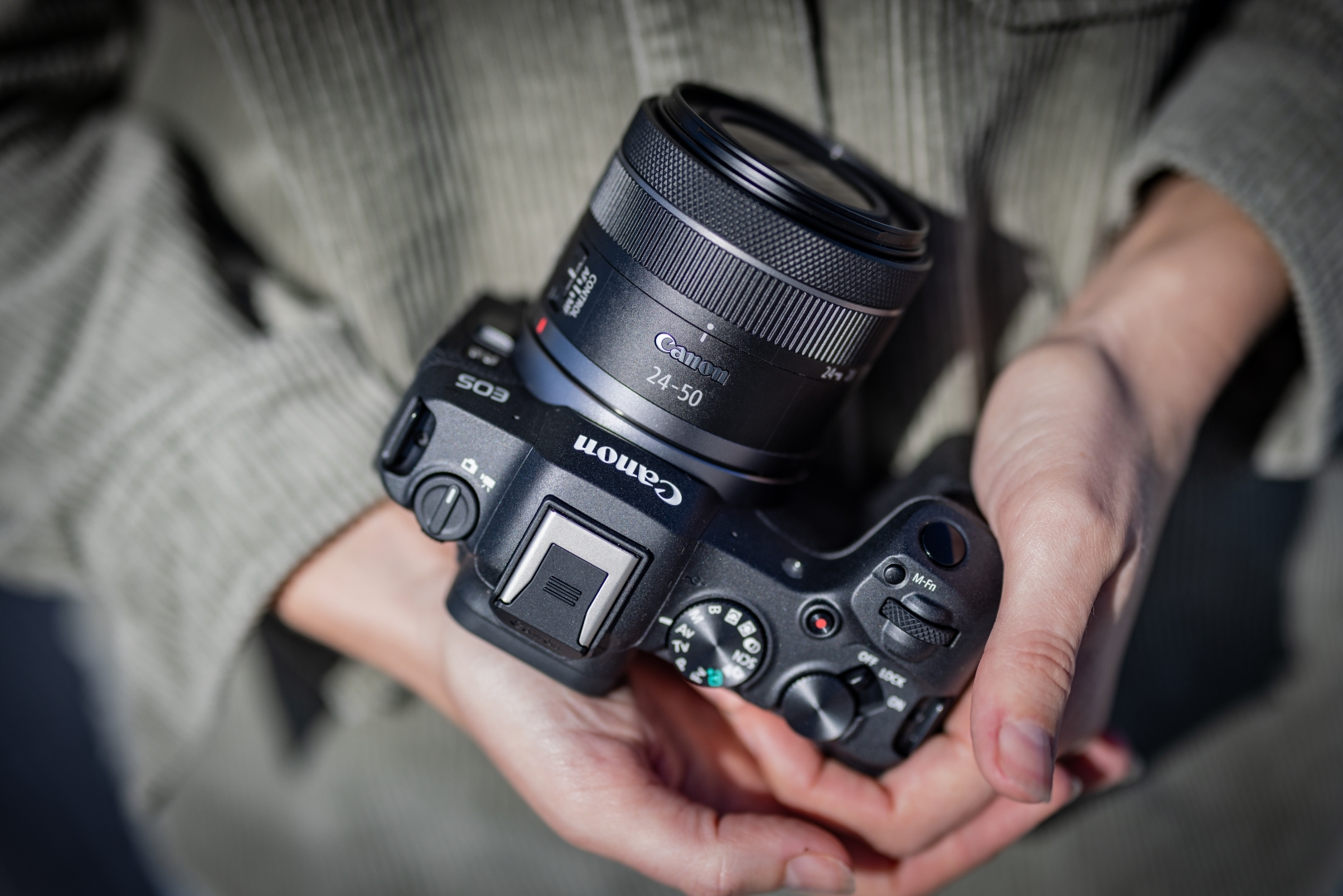 Eine Canon-Kamera mit 24-50-mm-Objektiv, gehalten in zwei Händen.