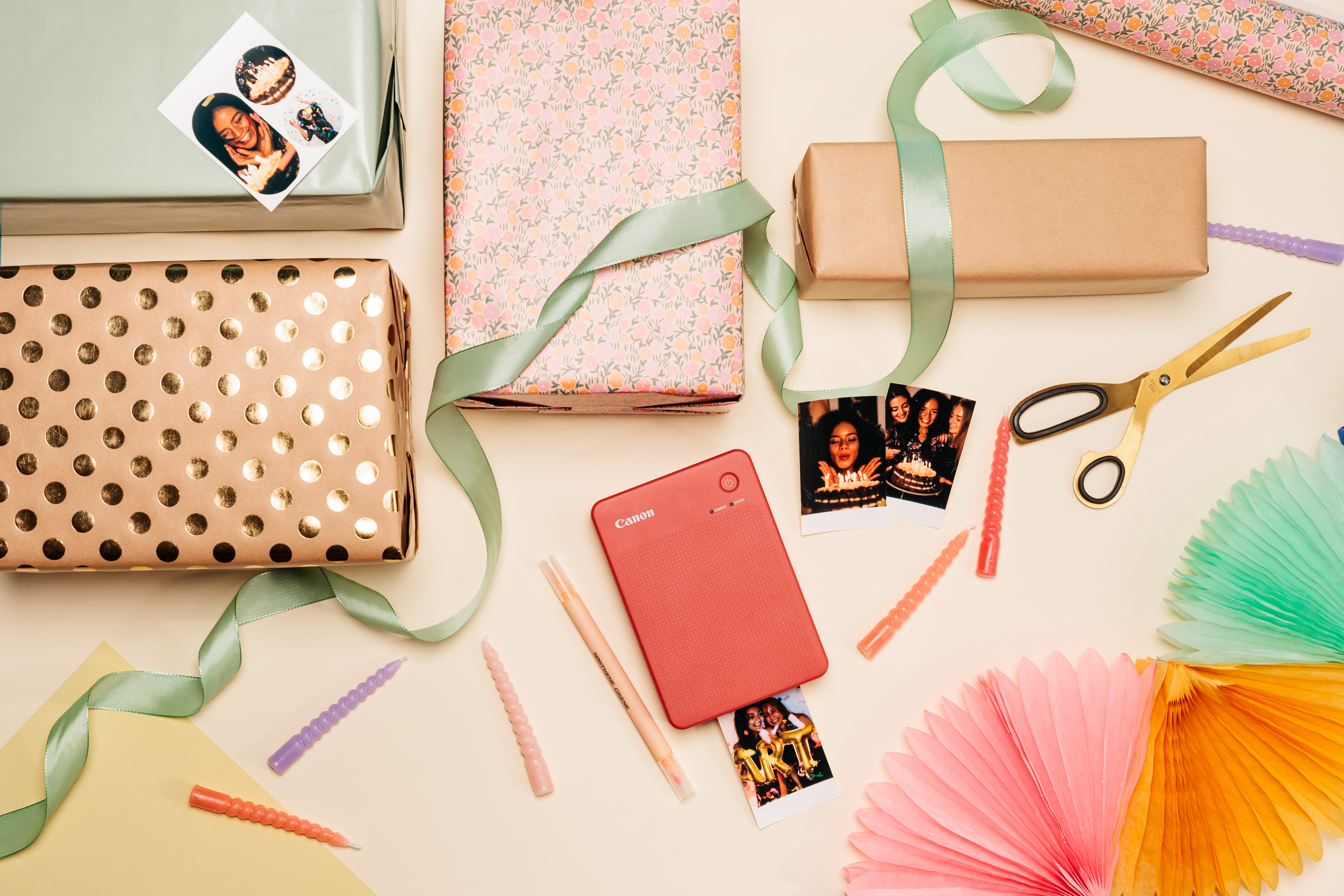 Geschenke, Fotos, Schere und Drucker auf beiger Oberfläche. Geschenke in verschiedenen Papieren verpackt. Bunt.