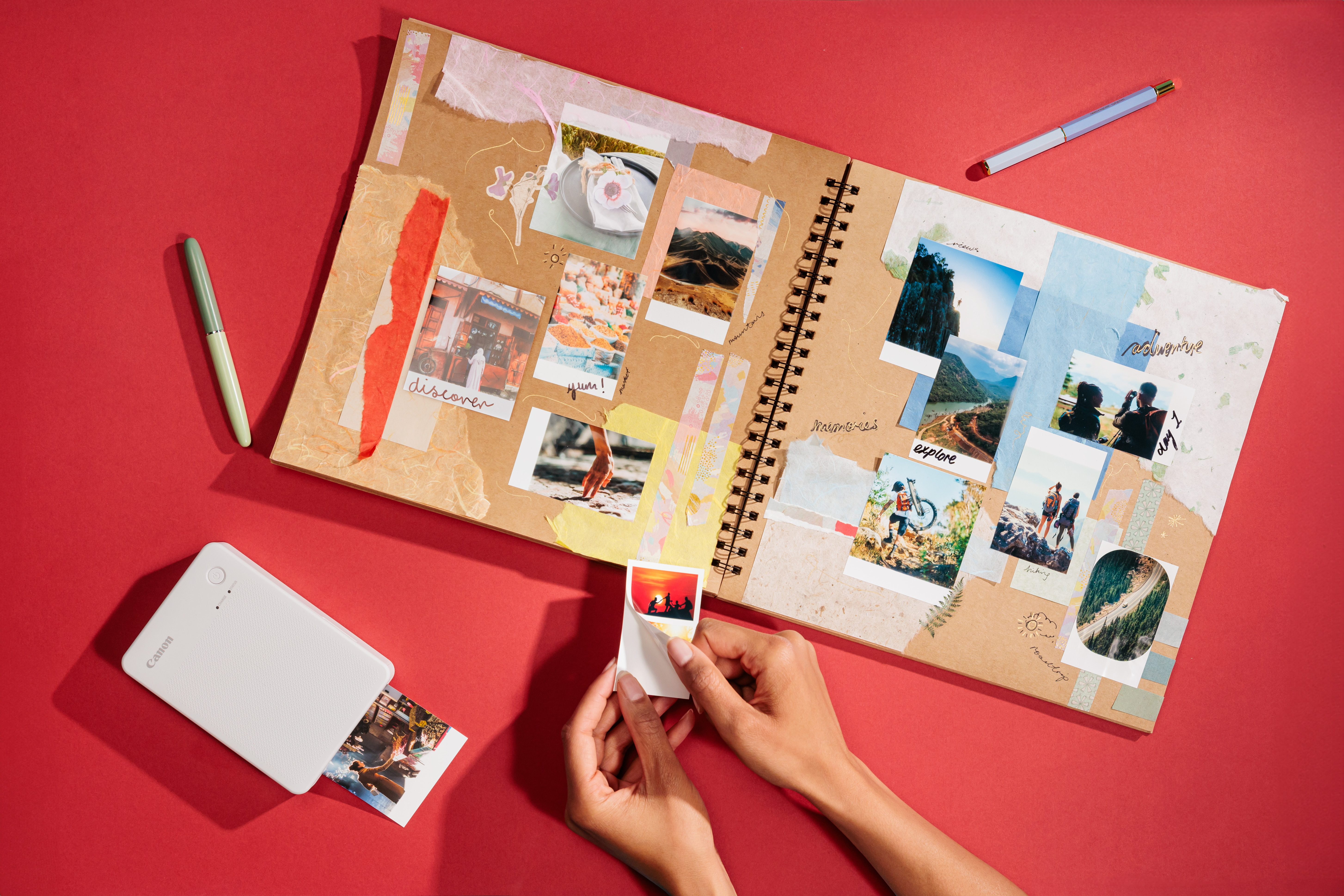 Ein Fotoalbum mit Fotos, Stiften und einem weißen Canon Selphy-Drucker.