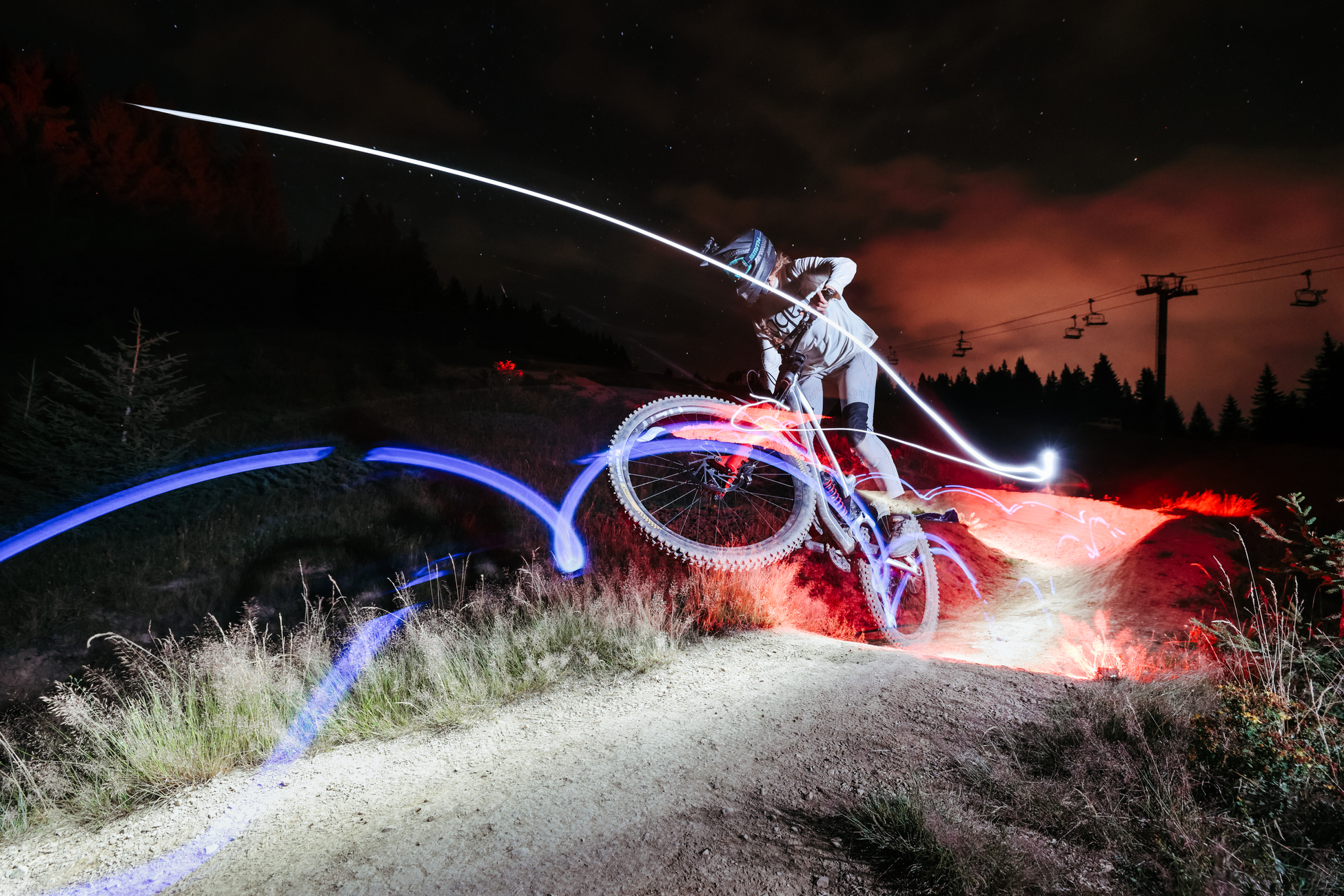 Mountainbiker fährt nachts mit Lichtspuren.