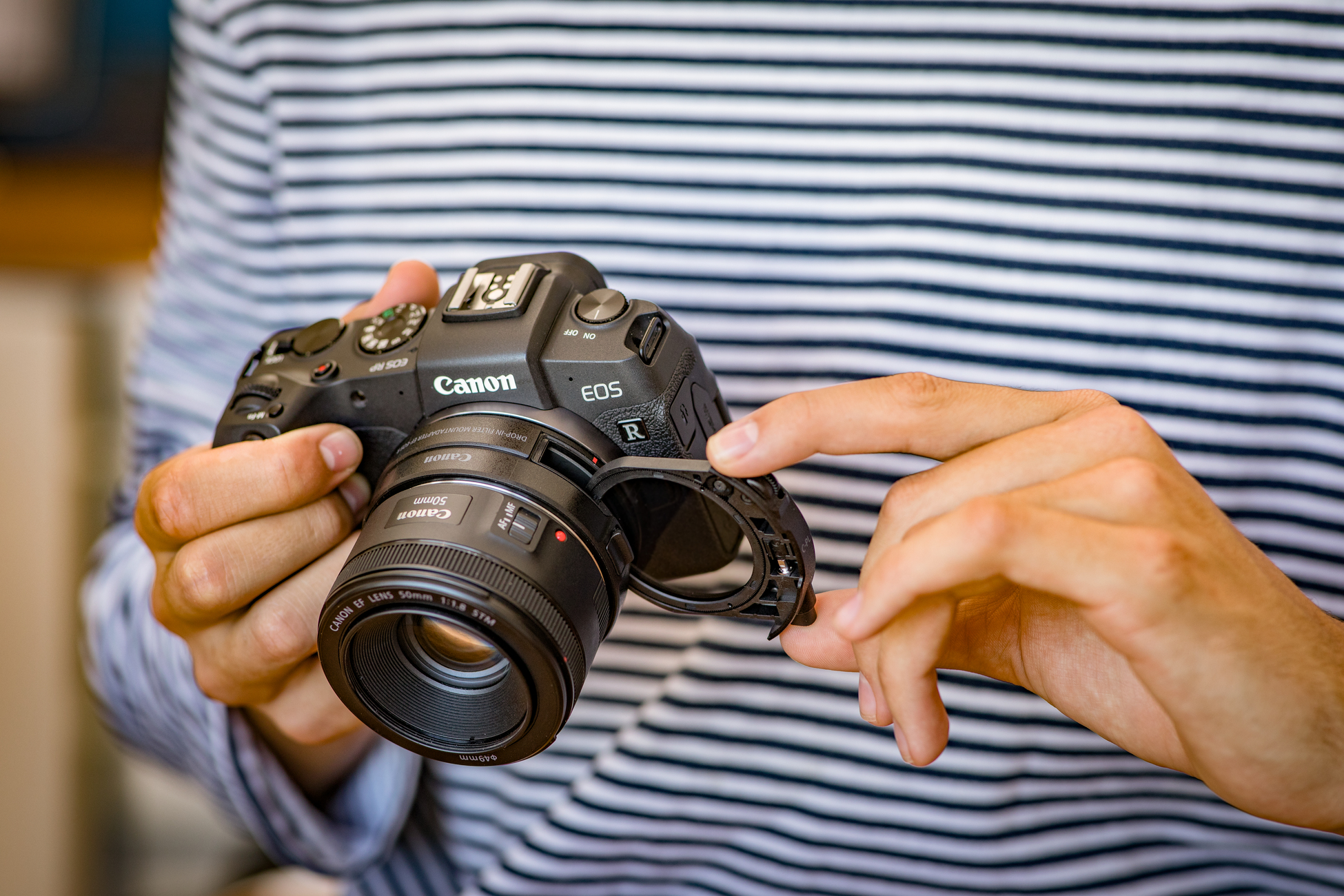 Eine Person hält eine Canon Kamera mit Objektiv und Filter.
