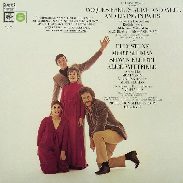 Pochette d'album avec quatre personnes debout, souriant et regardant la caméra. Tons rouges et marrons.