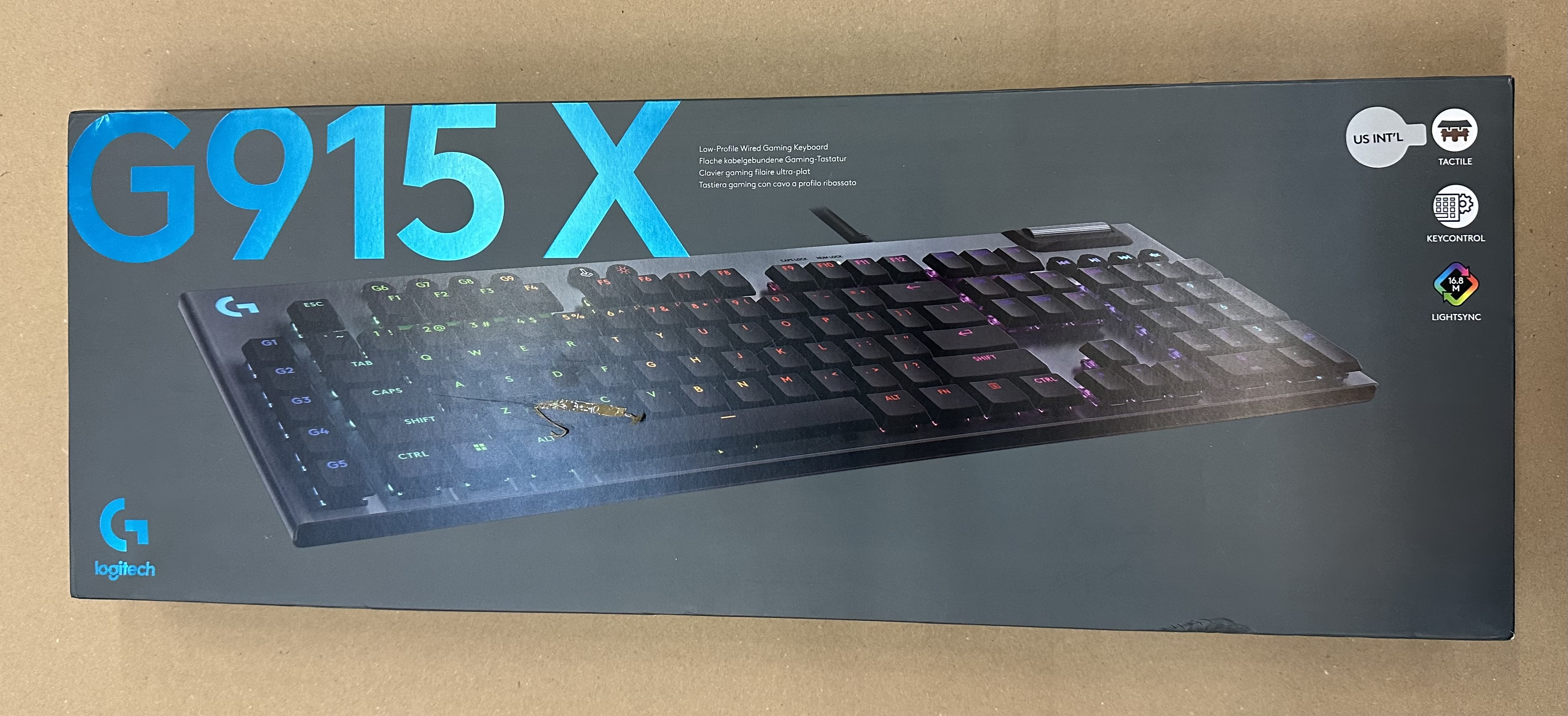 Czarne pudełko, klawiatura Logitech G915 X w środku, z etykietami US INT'L i LightSync.