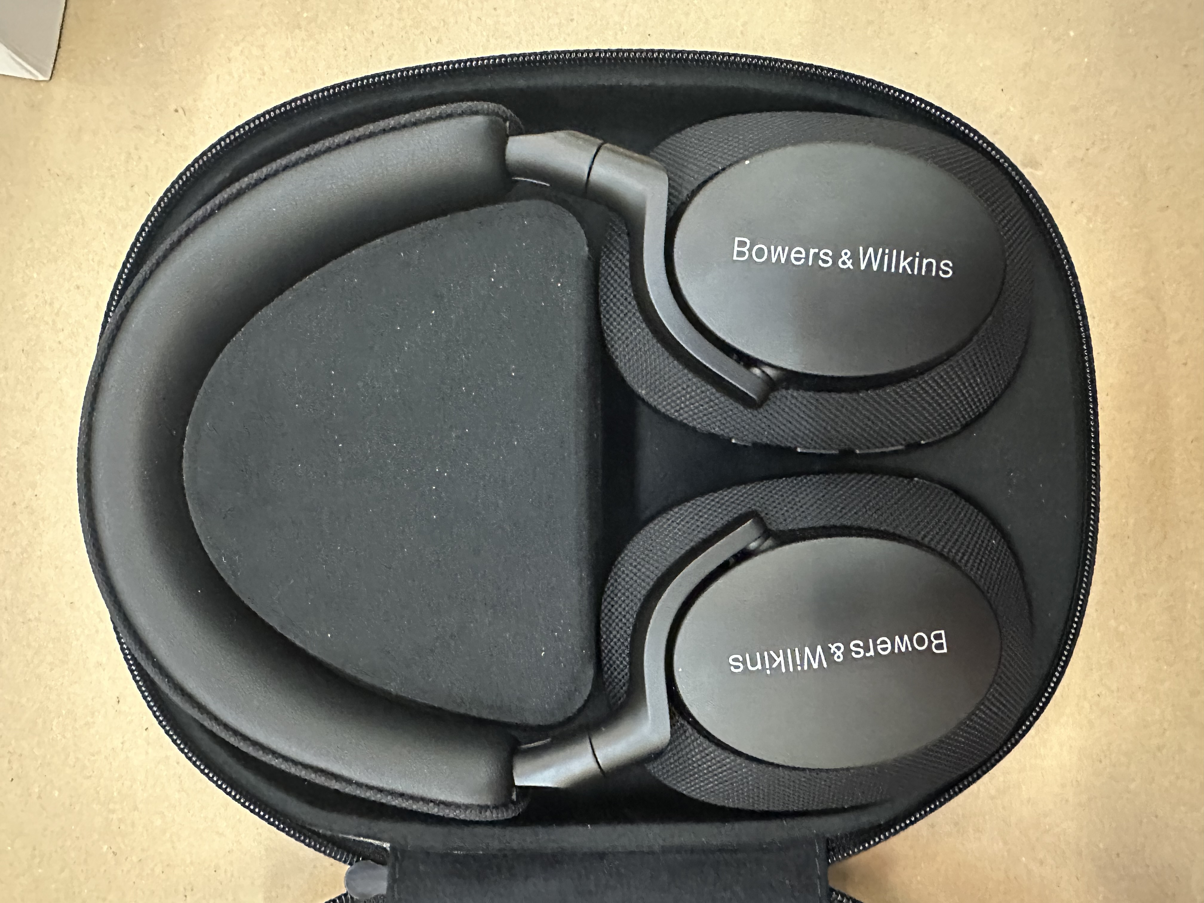 Otwarte etui na słuchawki ze słuchawkami Bowers & Wilkins w środku, czarne.