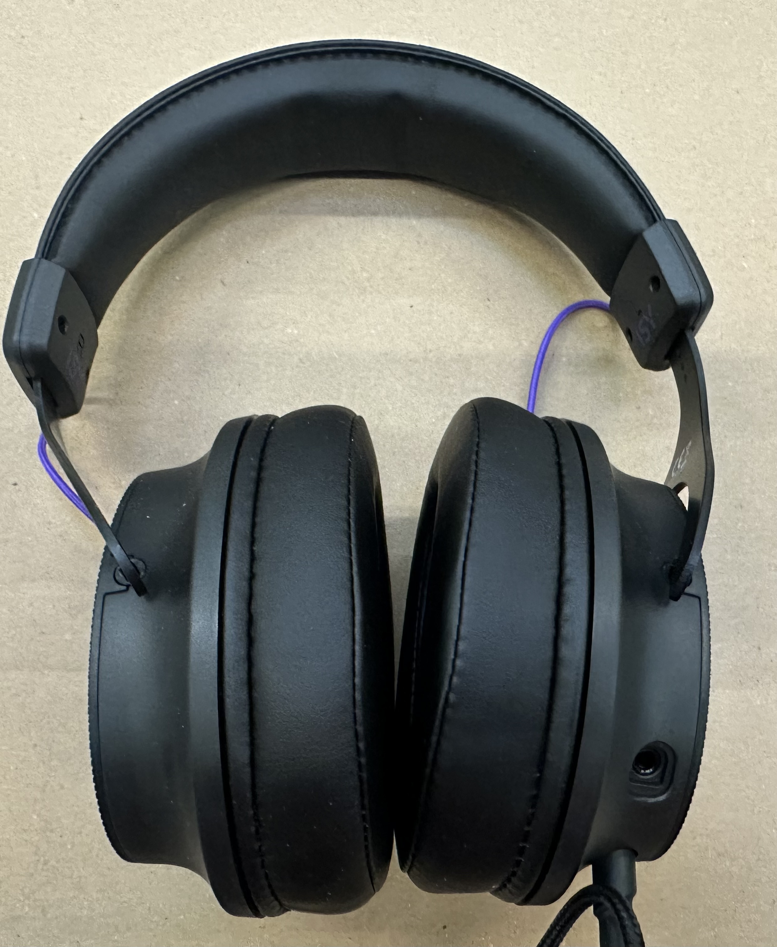 Czarne słuchawki z fioletowym kablem, widok z góry.