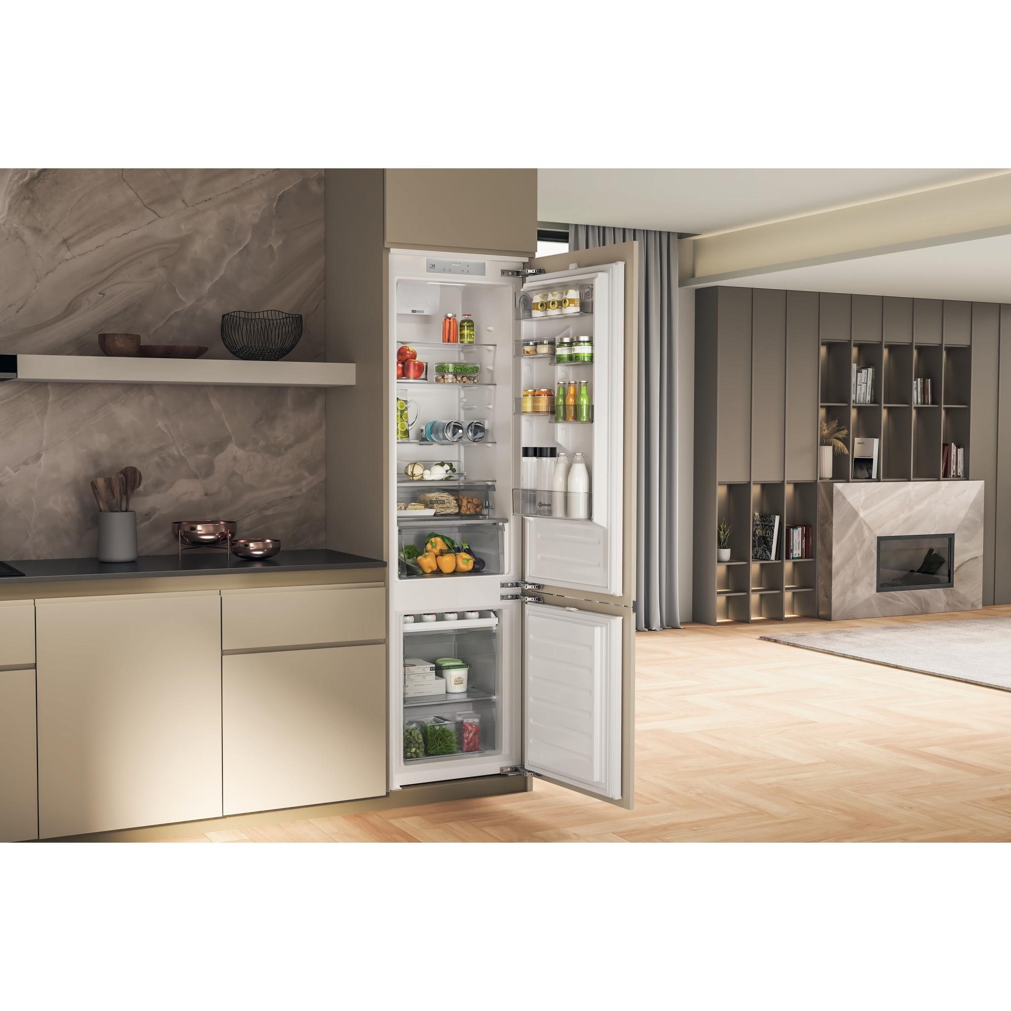 Küche mit offenem Kühlschrank. Gefüllt mit Essen. Schränke, Marmorwand und Fenster.