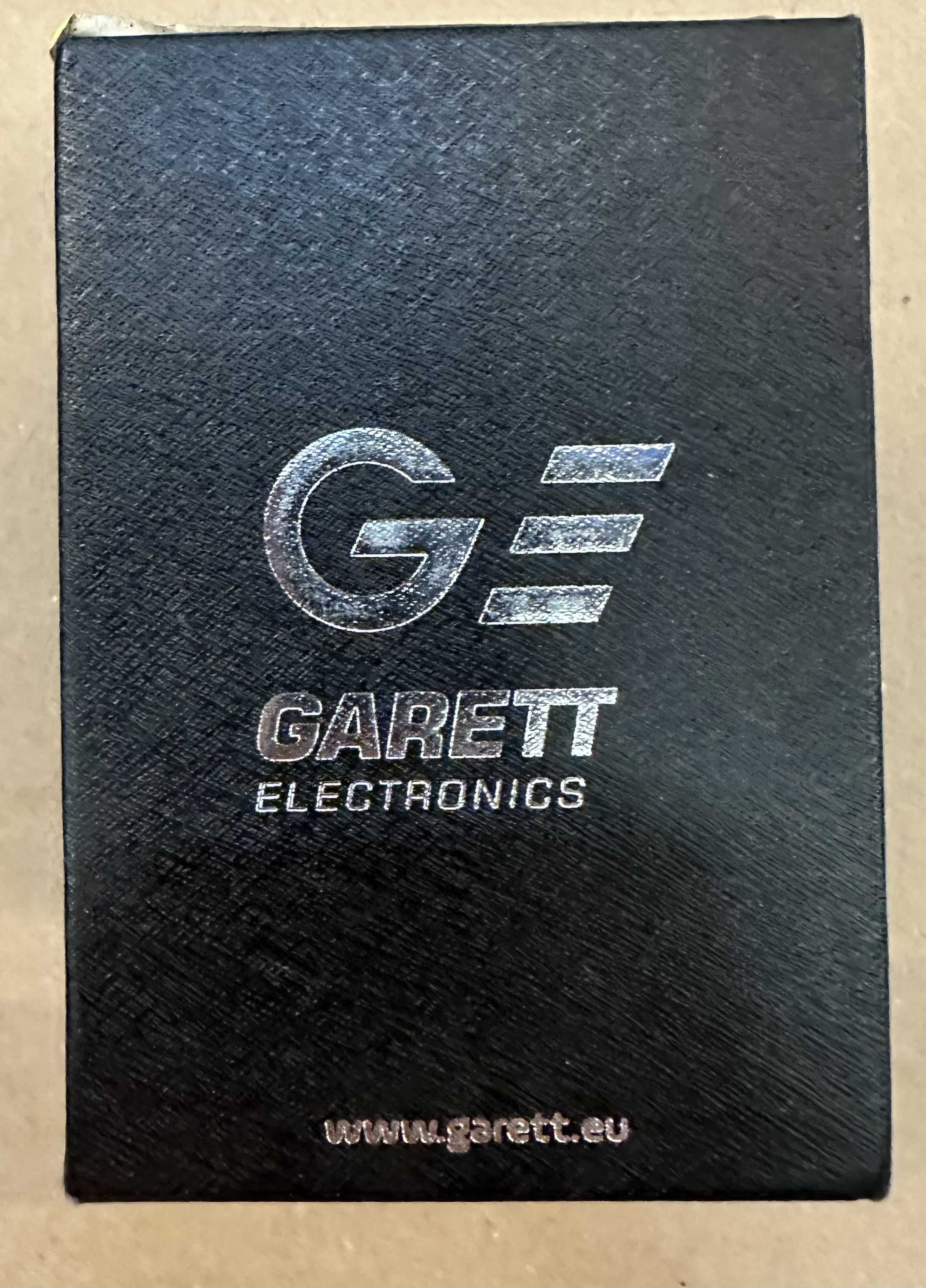 Czarne pudełko ze srebrnym logo i tekstem, "GARETT ELECTRONICS" i strona internetowa.