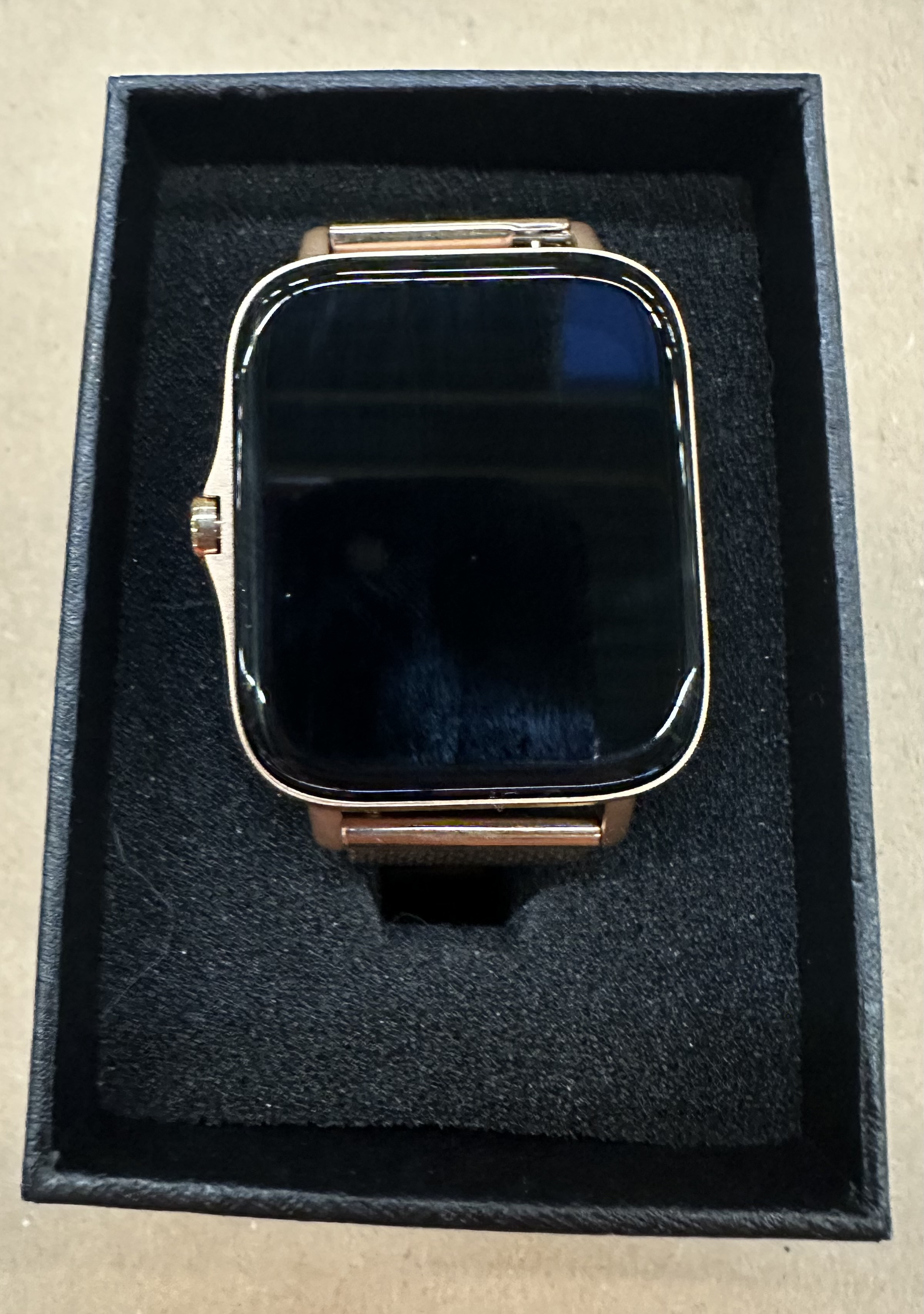 Zegarek smartwatch w kolorze różowego złota na czarnym tle.