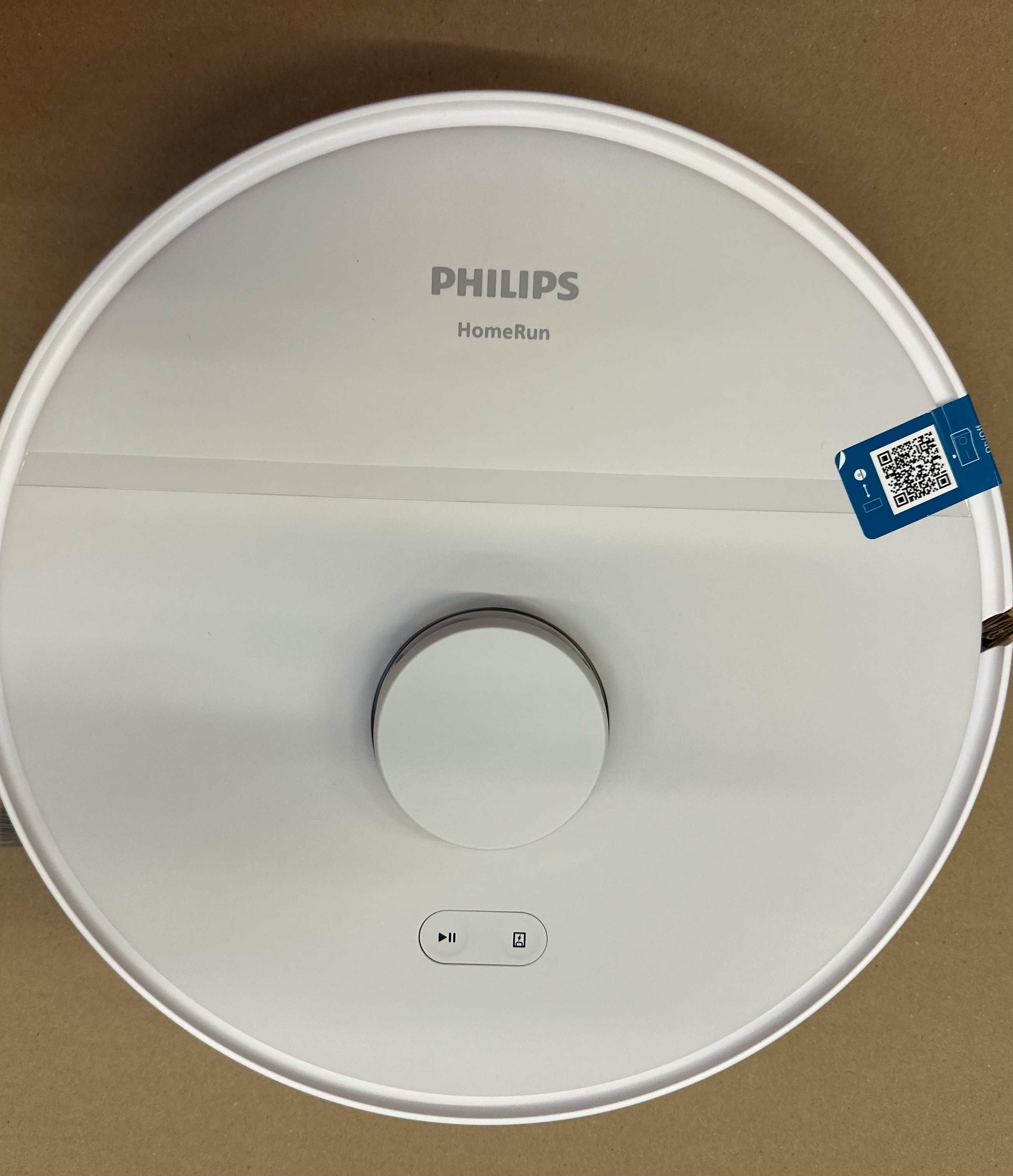 Biały robot sprzątający Philips HomeRun z naklejką z kodem QR i przyciskami.