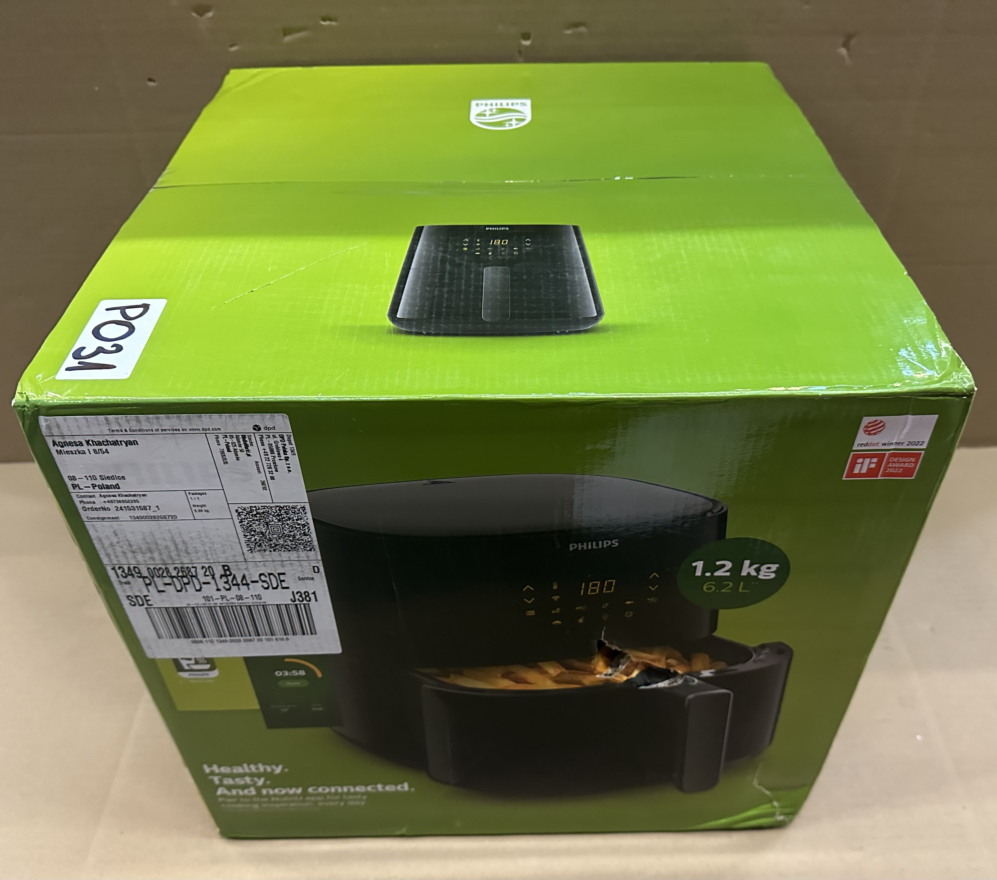 Zapakowany Philips Airfryer, zielony i czarny z tekstem. Wnętrze, neutralna powierzchnia.