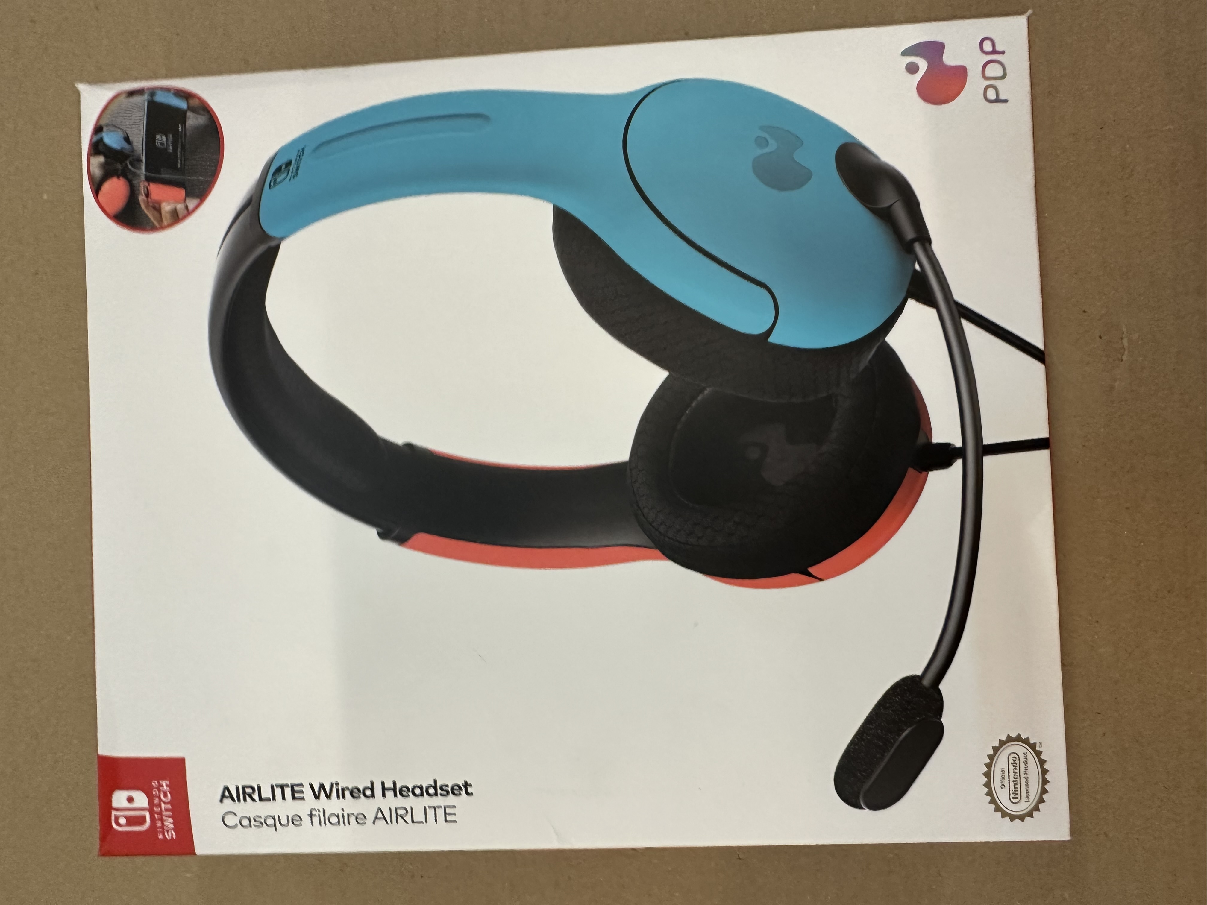 Pudełko przedstawiające przewodowy zestaw słuchawkowy AIRLITE. Zestaw jest niebiesko-czarny.