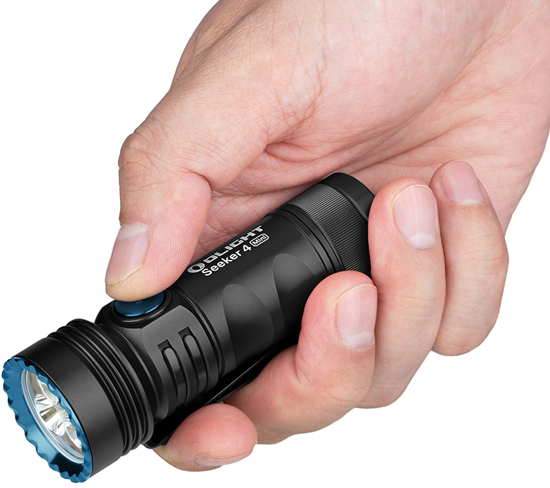 Eine Hand hält eine schwarze Taschenlampe mit blauem Knopf. Auf der Taschenlampe steht 'OLIGHT Seeker 4 Mini'.
