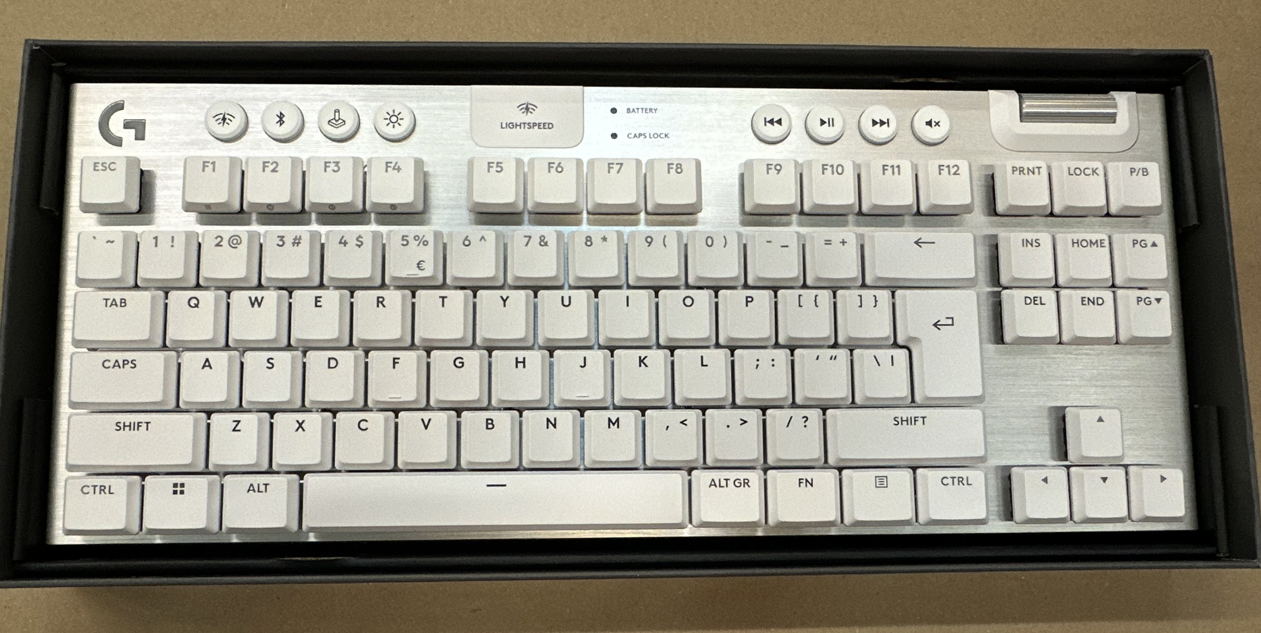 Biała i srebrna klawiatura mechaniczna Logitech w pudełku, z różnymi klawiszami i przyciskami funkcyjnymi.