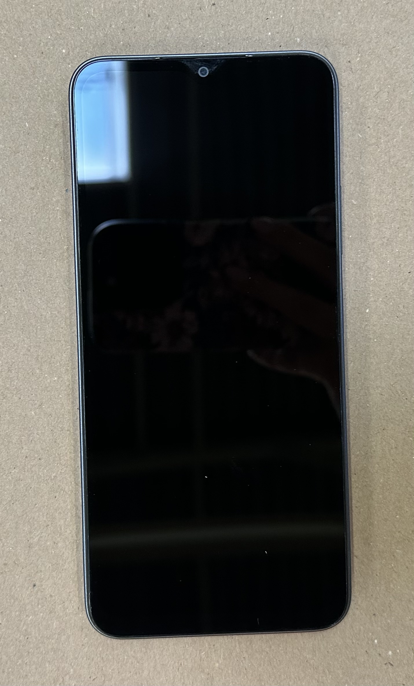 Telefon z czarnym ekranem. Jest wyłączony, z małym przednim aparatem.