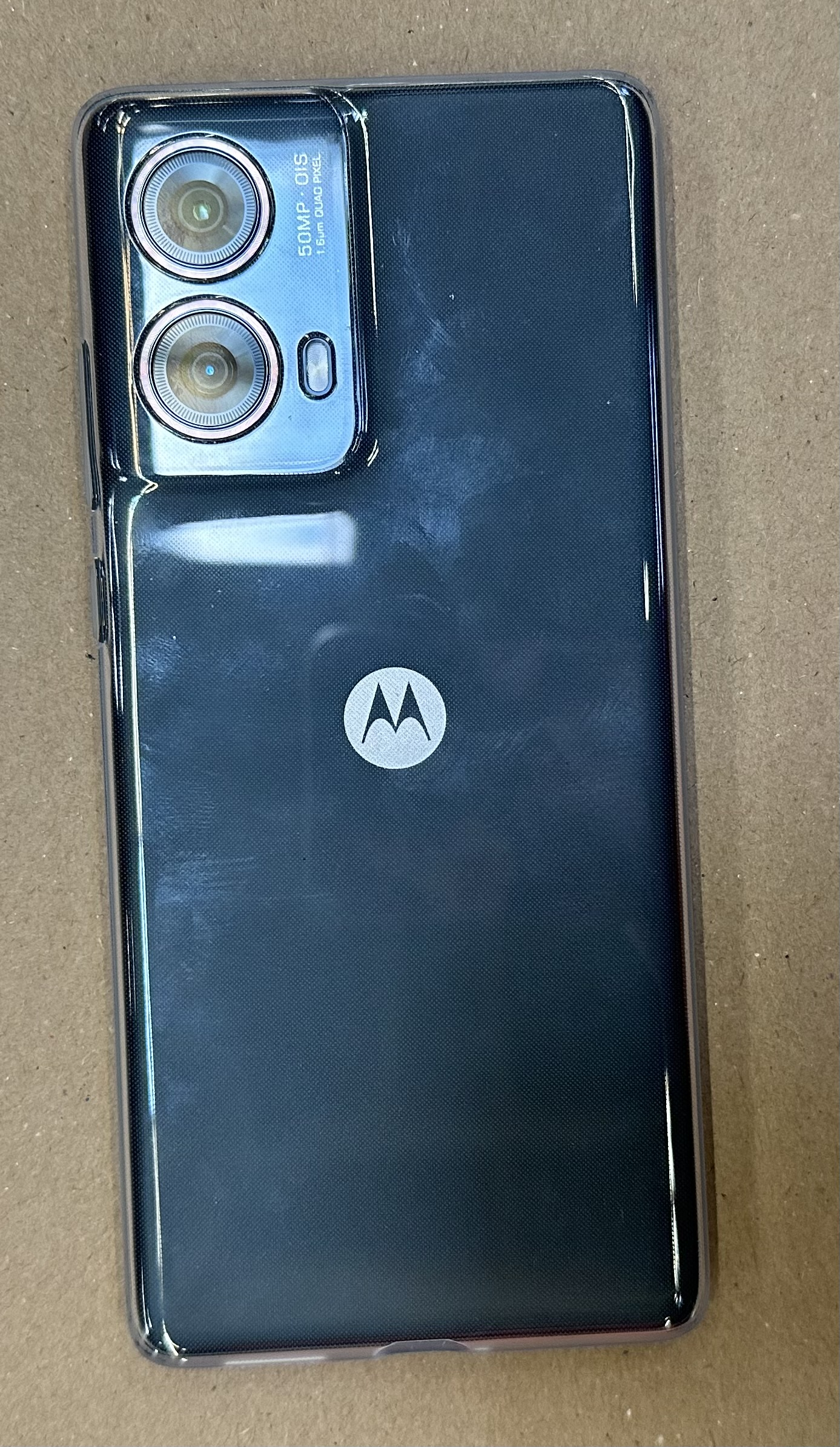 Tył czarnego telefonu w etui. Ma dwa aparaty i logo Motorola.