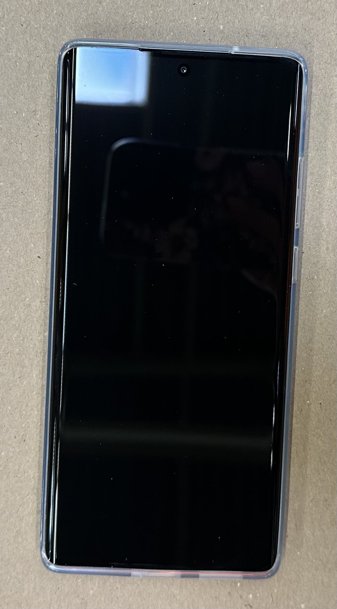 Czarny smartfon z ekranem, na powierzchni, z przezroczystym etui ochronnym.