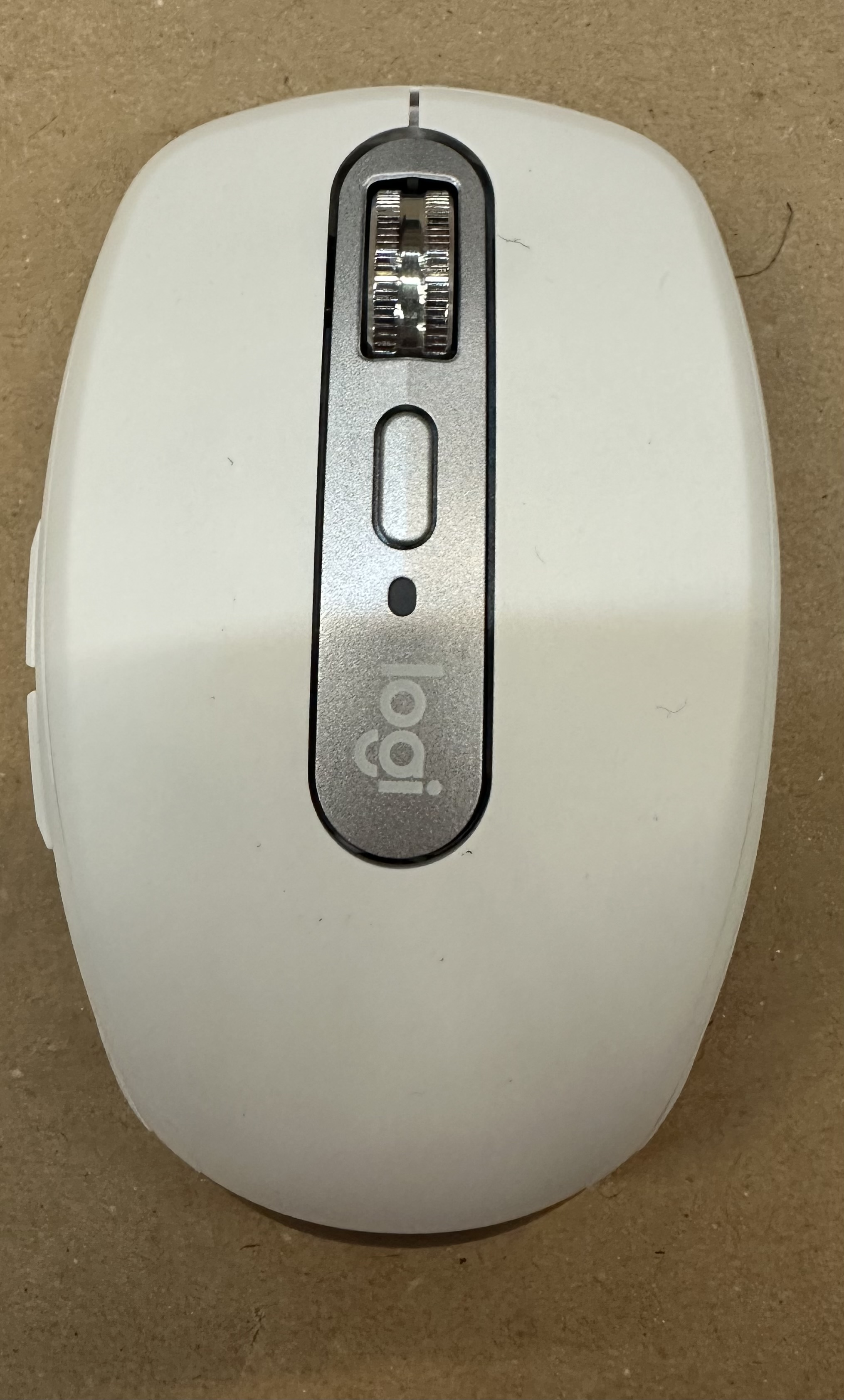 Biała mysz Logitech z kółkiem i przyciskami na brązowym tle.