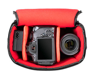 Otwarta torba na aparat z aparatem, obiektywem i baterią w środku.