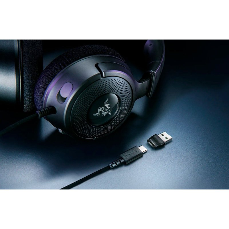 Auriculares Razer negros con cable de carga y adaptador USB sobre una superficie.