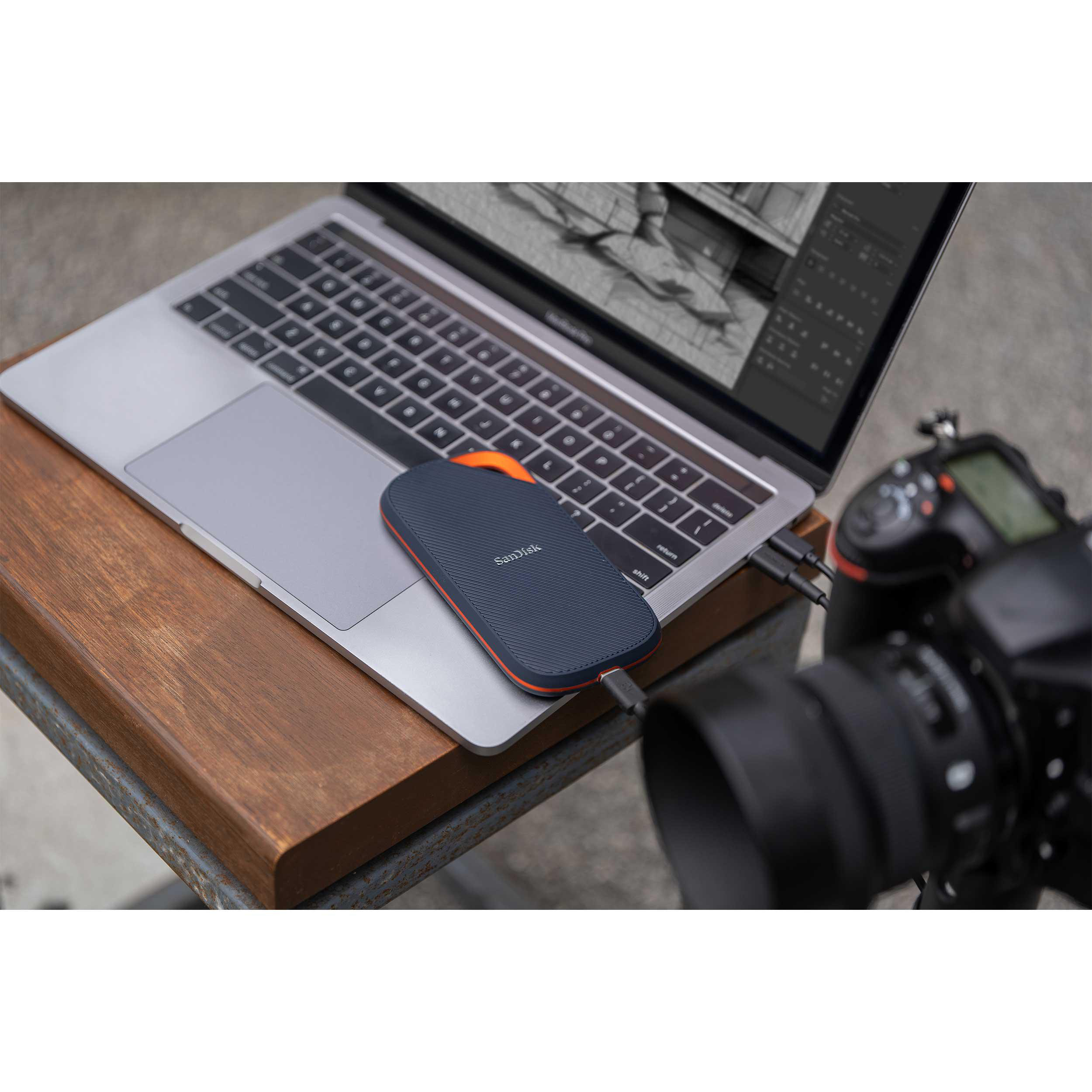 Laptop mit externer Festplatte verbunden, neben einer Kamera auf einem Tisch.