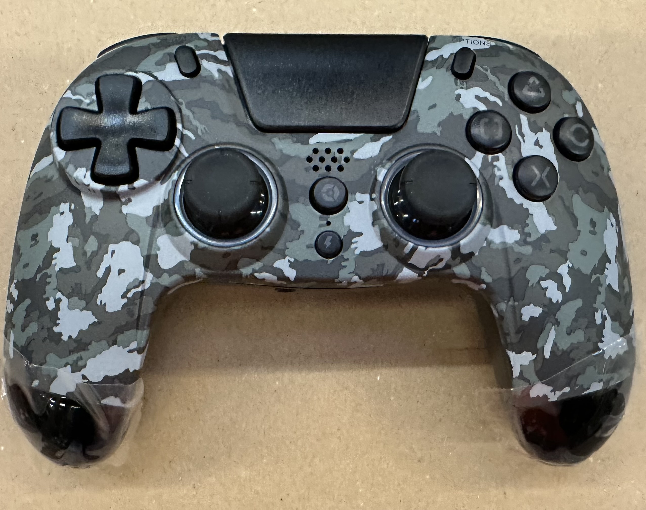 Pad do gier w kamuflażu. Jest szary i czarny, widoczne są standardowe przyciski.