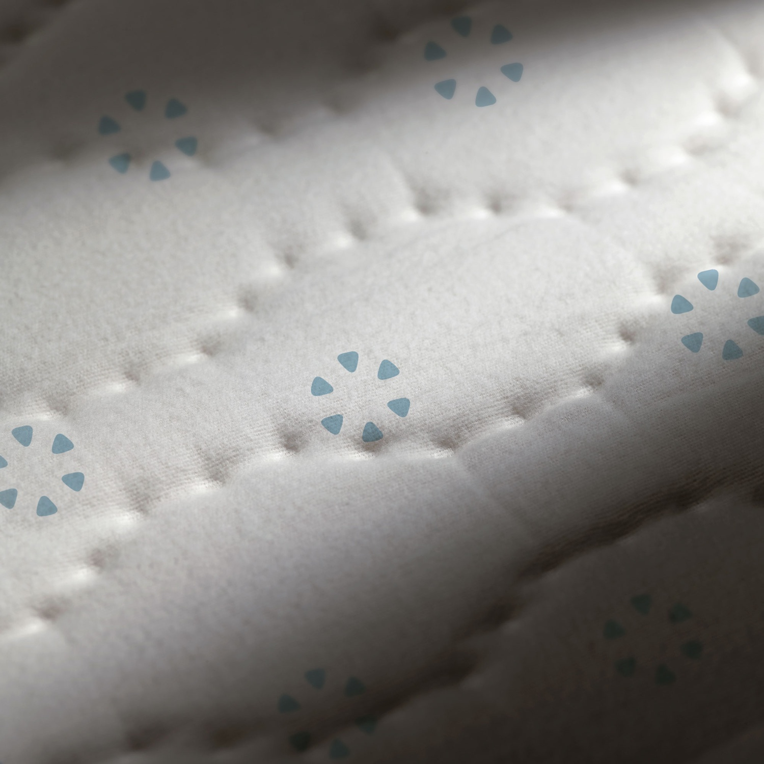 Primo piano di tessuto bianco trapuntato con motivi a triangoli blu.