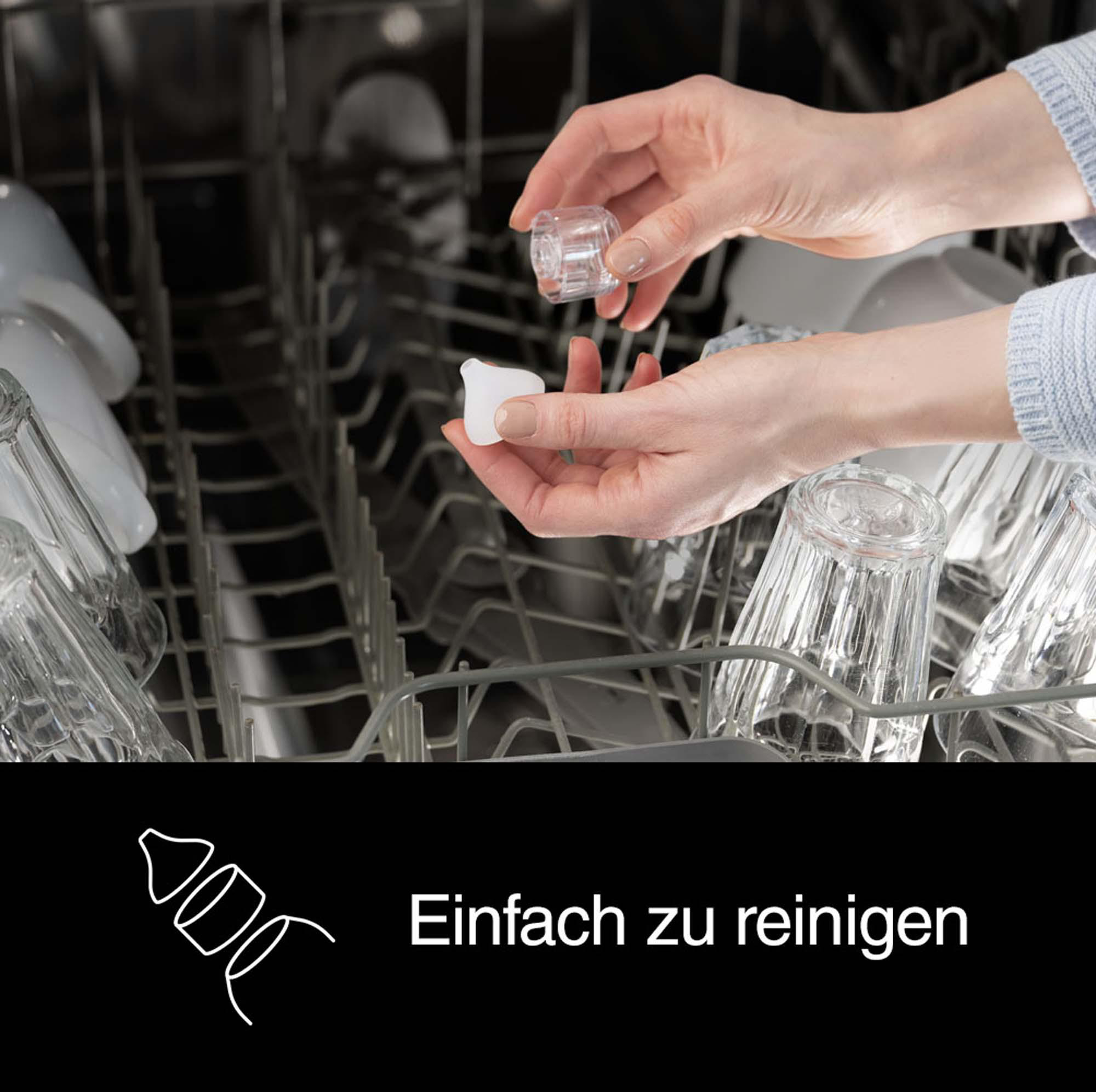 Hände einer Person, die zwei spülmaschinenfeste Teile einer Maschine halten und zeigen.