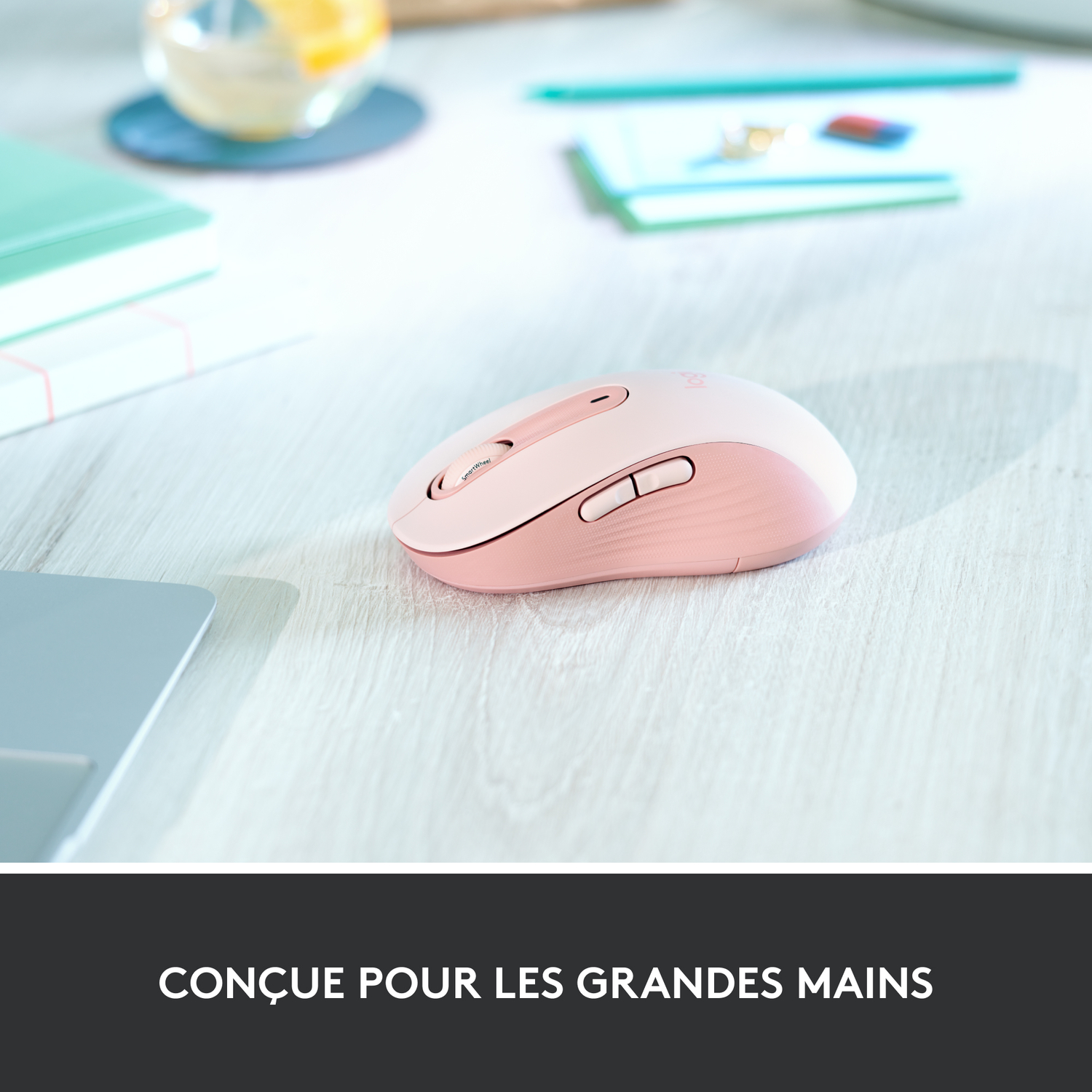 Souris rose sur un bureau blanc. Texte: Conçu pour les grandes mains.