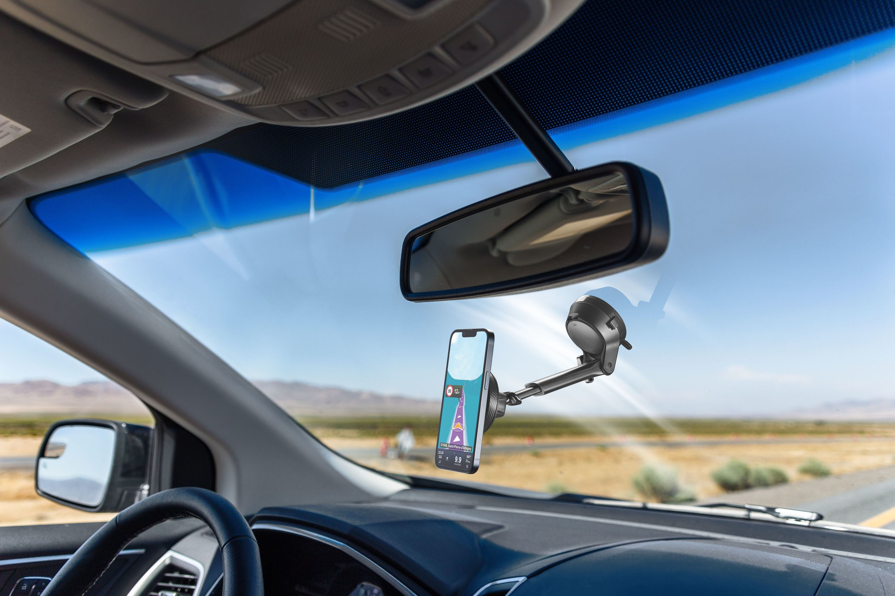 Araba içi. Telefon, navigasyon uygulamasını gösteren bir araç tutucusuna monte edilmiştir. Ön cam, direksiyon ve yol görünür.