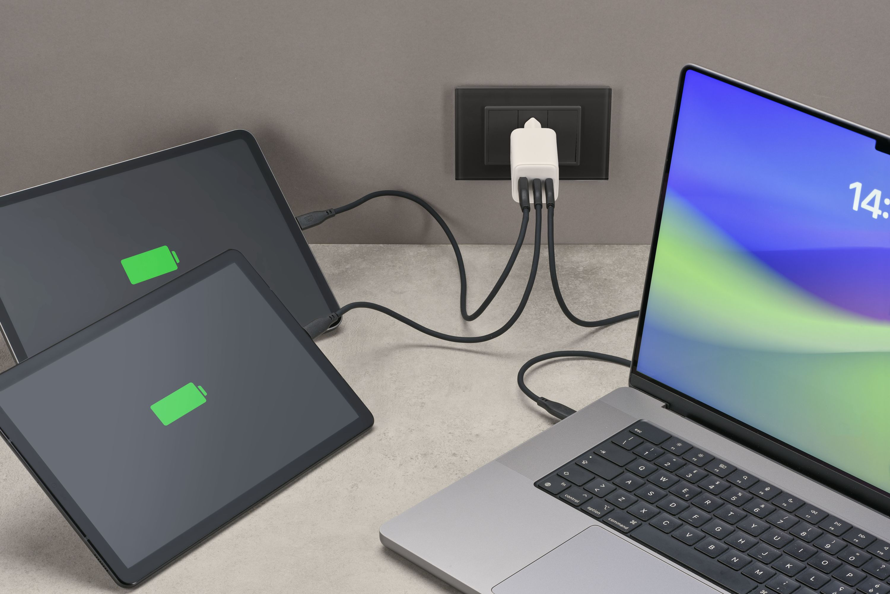 Cihazlar şarj oluyor: 2 tablet ve bir dizüstü bilgisayar, bir duvar prizine takılı beyaz bir şarj cihazına bağlı.