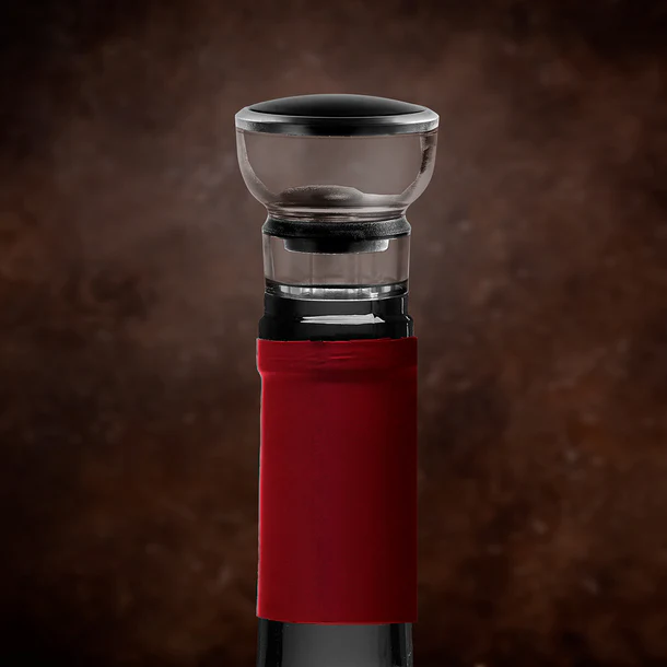 Botella de vino con etiqueta roja. Un aireador de vino en la parte superior. Fondo marrón borroso.