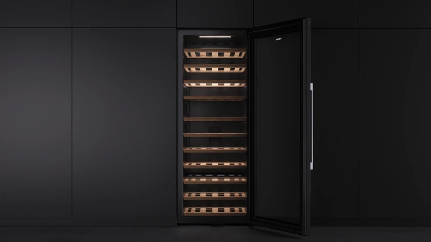 Un refrigerador de vino con la puerta abierta. Interior y exterior oscuros, estantes con madera. Manija en la puerta.