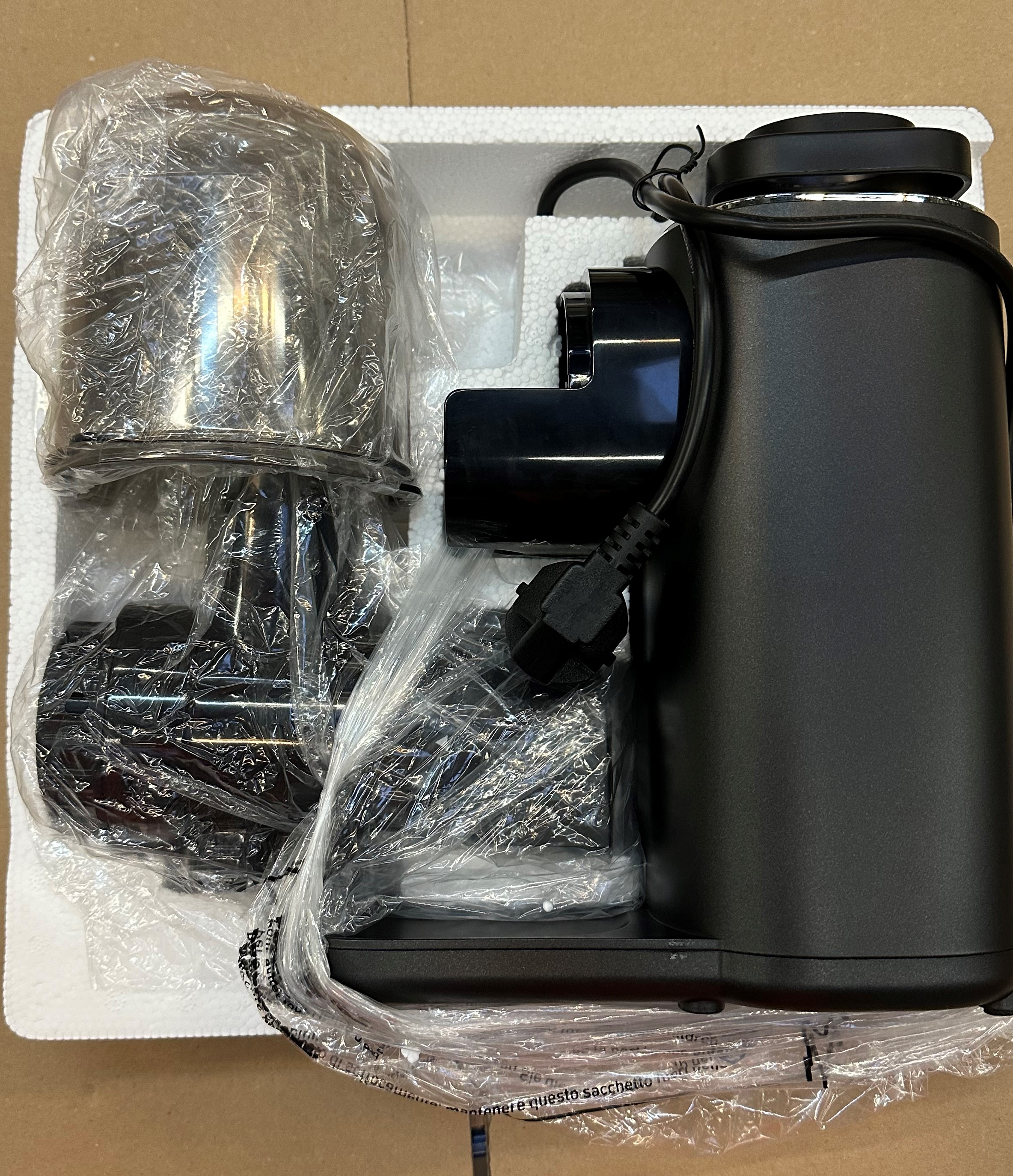 Czarny blender i jego części w białym opakowaniu. Blender stoi na powierzchni.