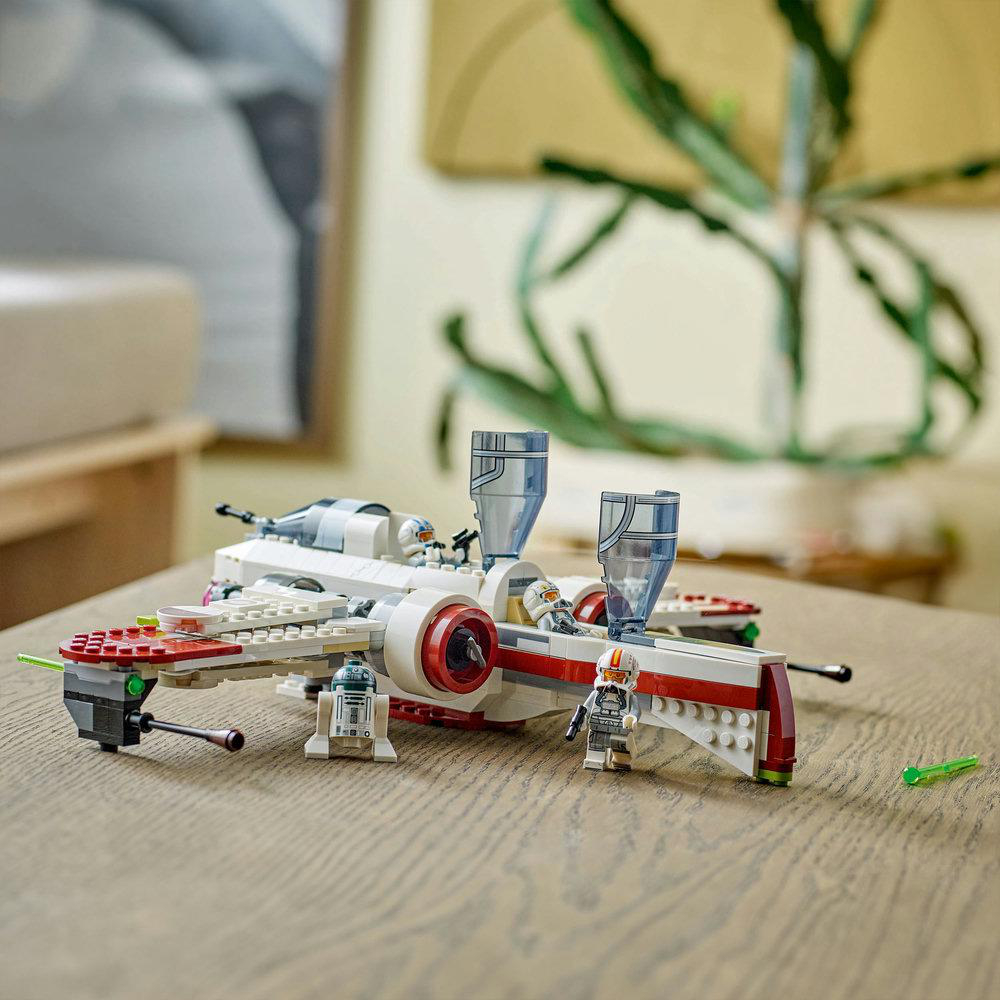 Lego-Set eines weiß-roten Raumschiffs mit Minifiguren auf einem Holztisch.