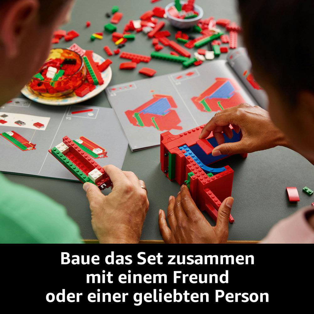 Zwei Personen bauen ein rotes Lego-Set mit Anweisungen. Rote, grüne und weiße Steine sind sichtbar.