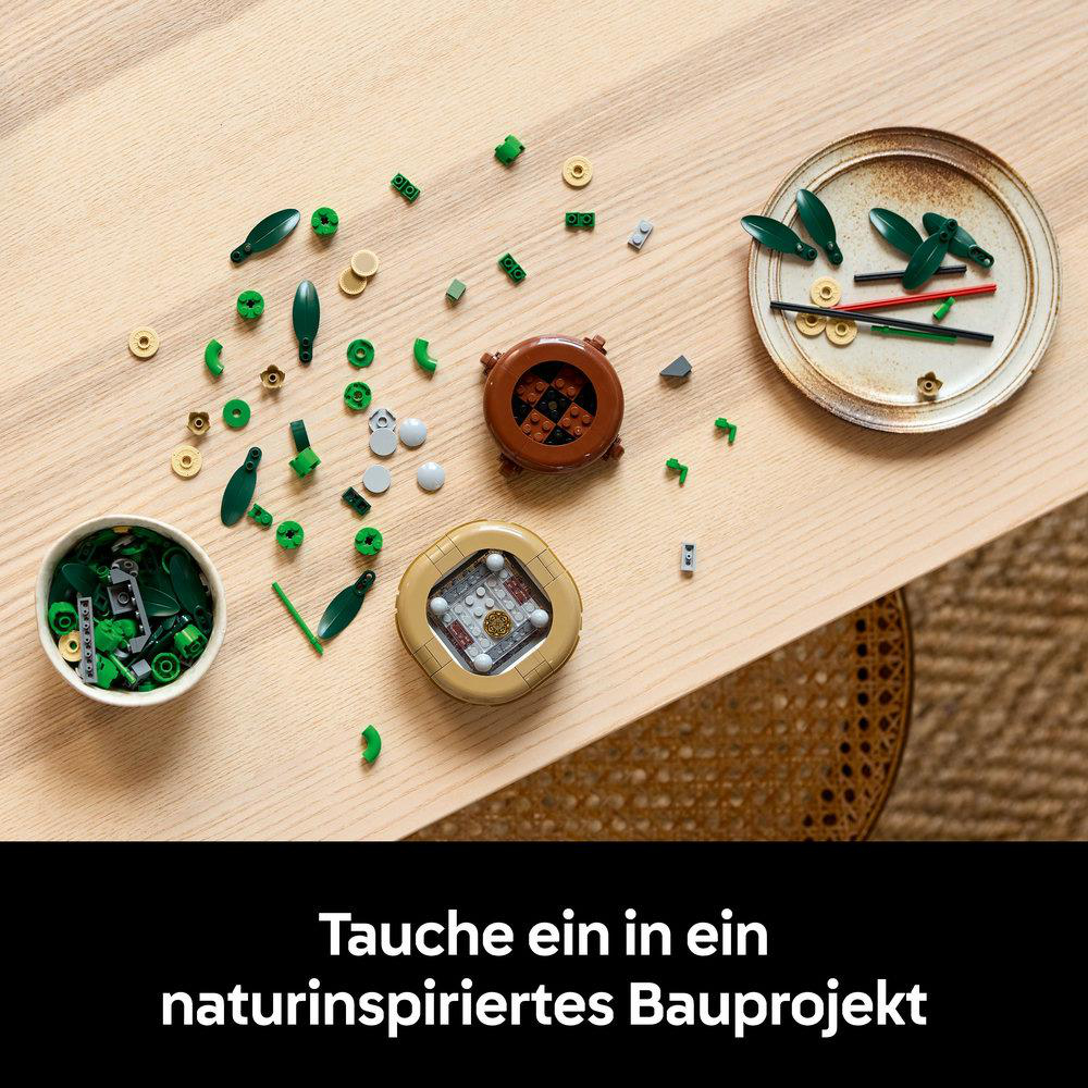Lego-Teile sind auf einem Holztisch verstreut. Die Teile sind grün, braun und beige.