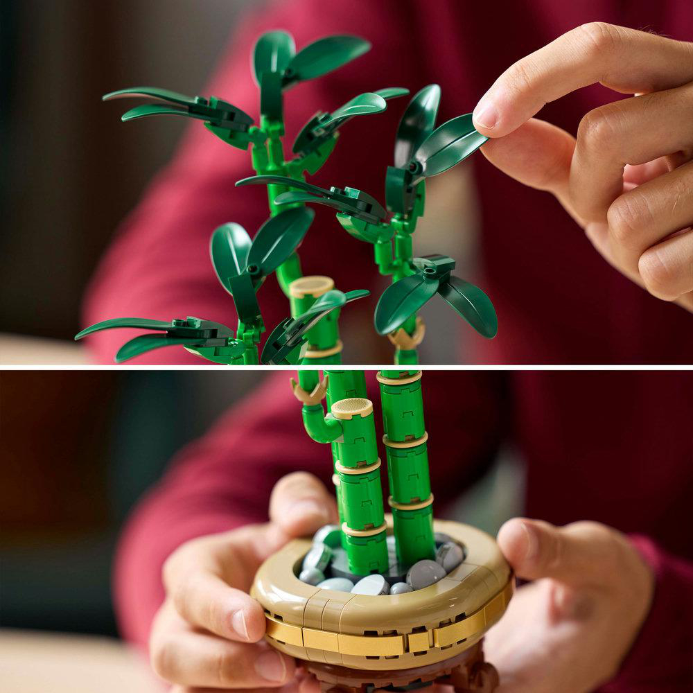 Hände, die Lego-Bambuspflanzen zusammensetzen, mit grünen Blättern und braunen Töpfen.