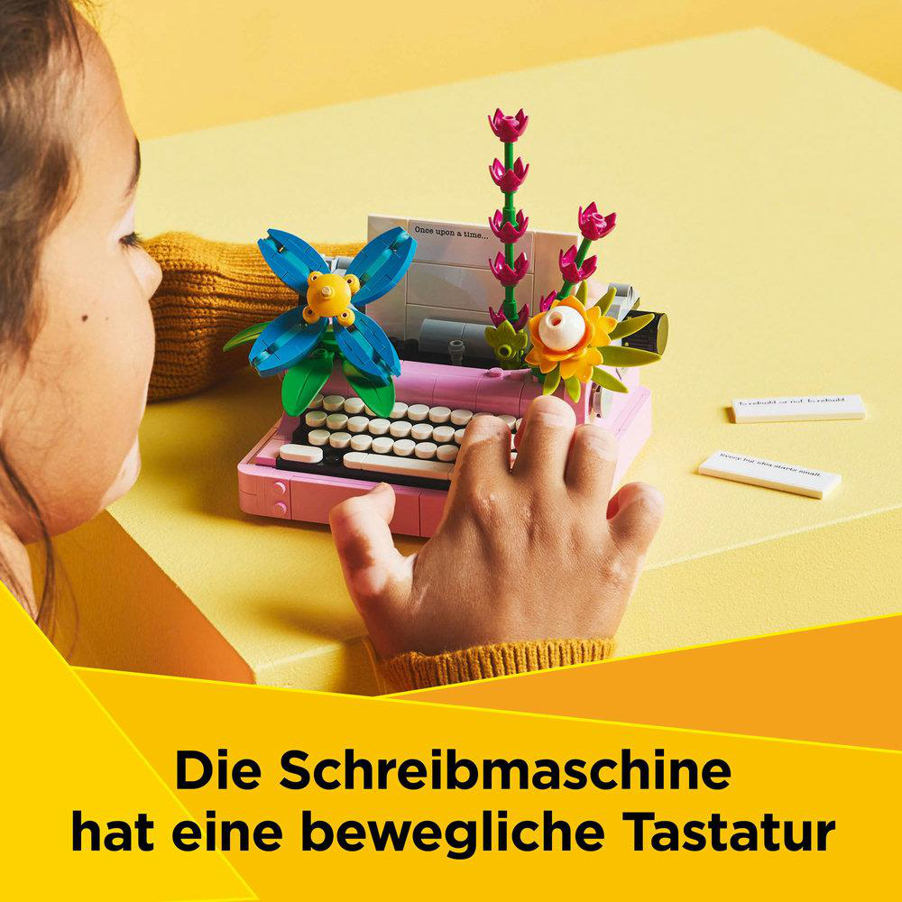 Kinderhände interagieren mit einem Lego-Schreibmaschinenmodell. Das Modell hat Blumen.