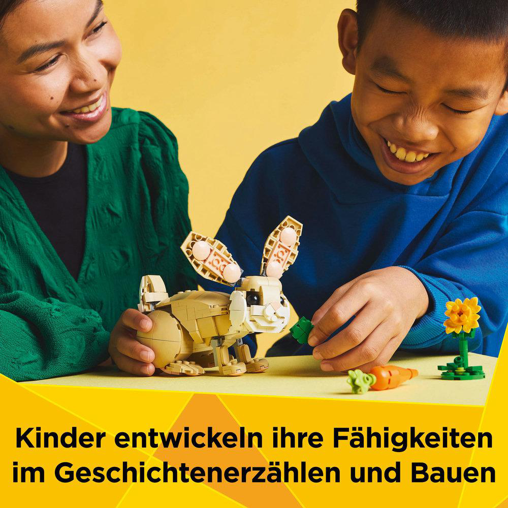Zwei lächelnde Kinder bauen ein Lego-Häschen mit Karotte. Gelber Hintergrund.