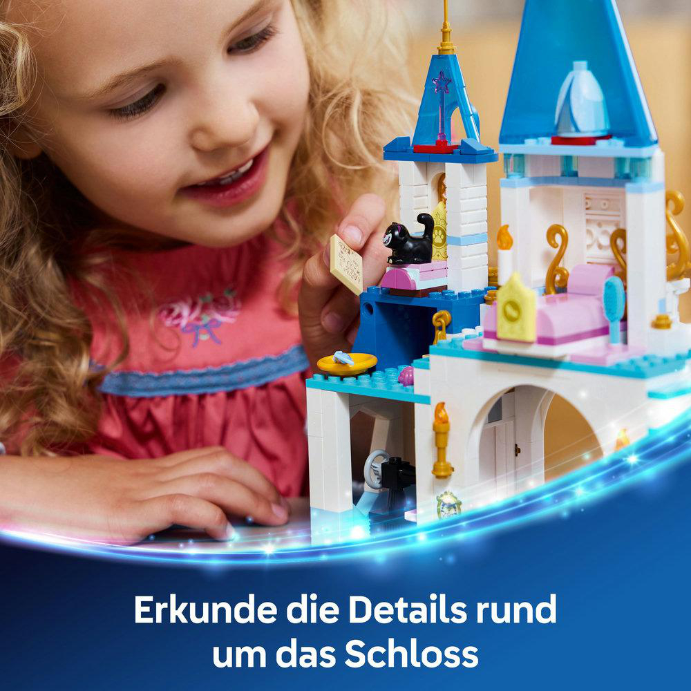 Ein kleines Mädchen lächelt, während es ein LEGO-Schloss betrachtet. Das Schloss ist weiß und blau.